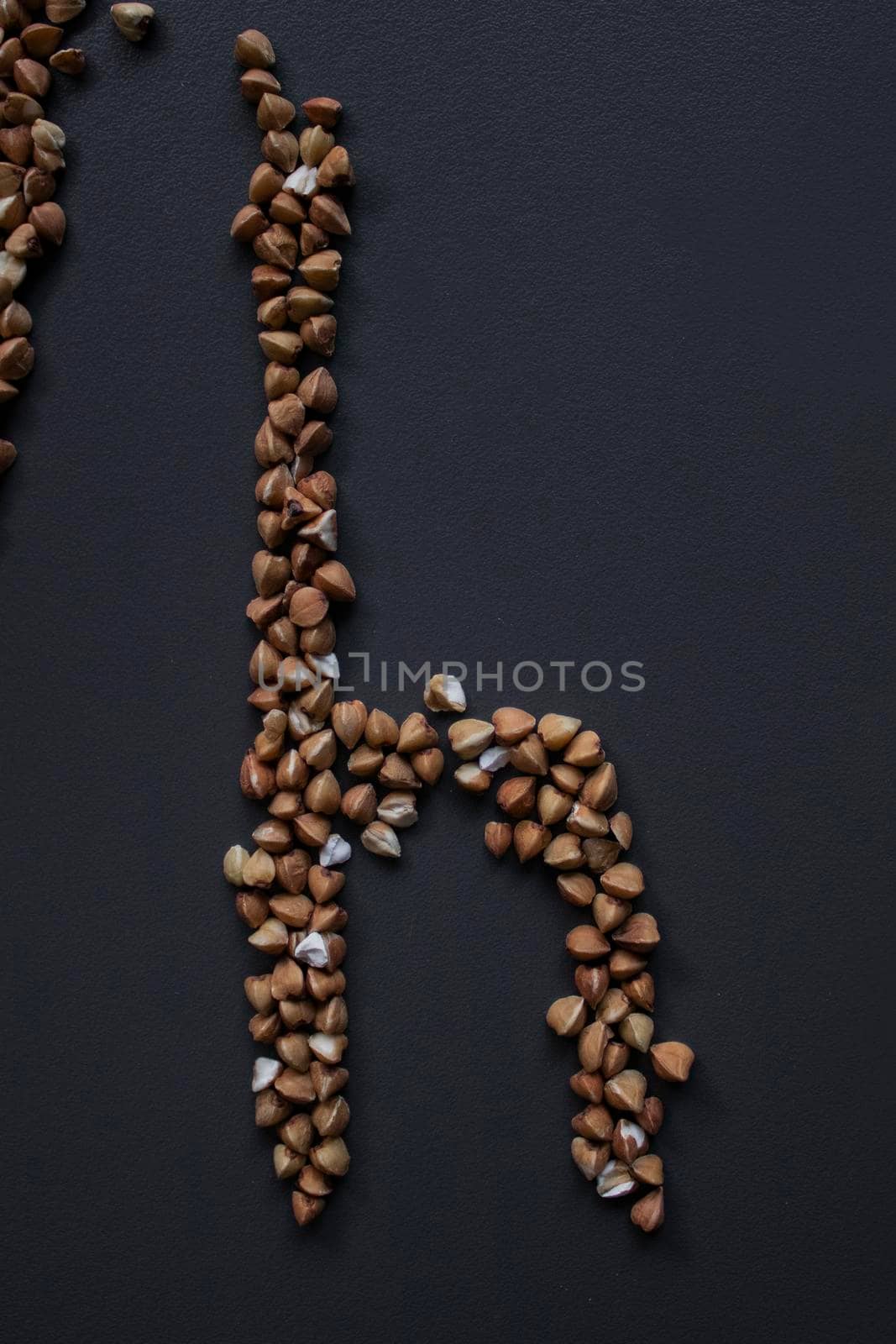 Letter 'h' written with buckwheat On gray background, top view, copy space. Food supplies crisis, food donation on quarantine isolation period