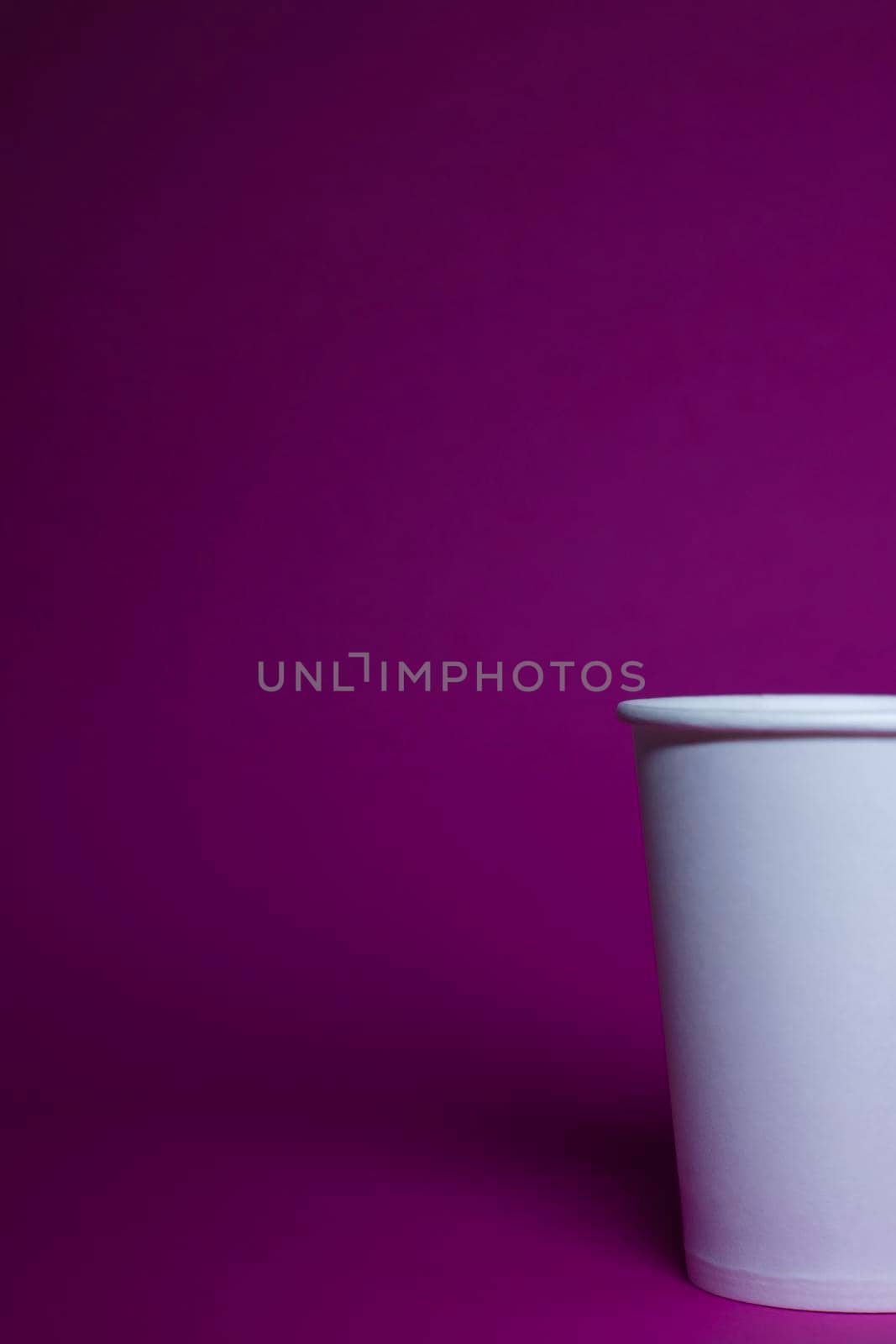 An empty white paper cup on a pink background. horizontal photo.