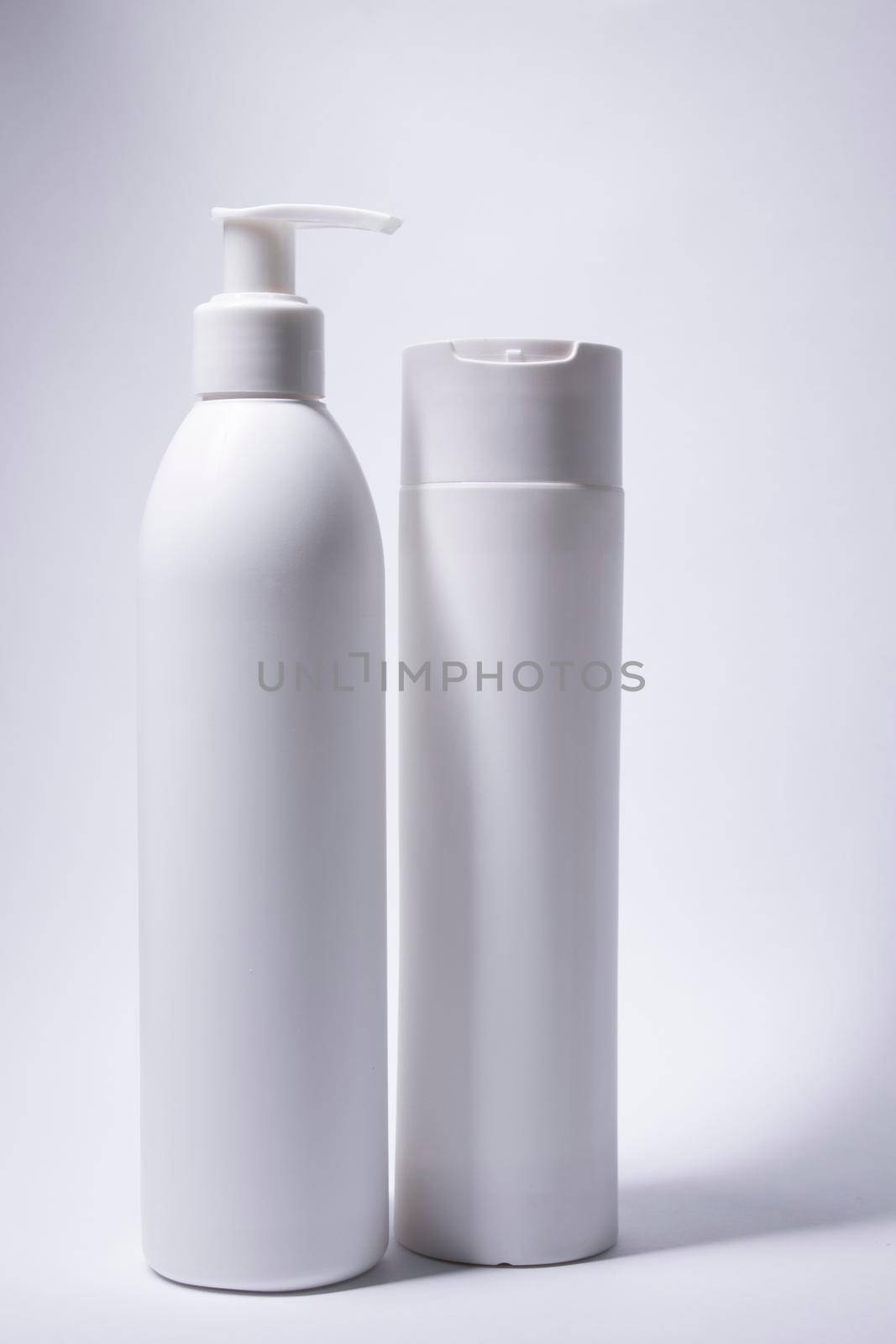 two white shampoo bottles and no label. body care and beauty concept. Copy space by oliavesna