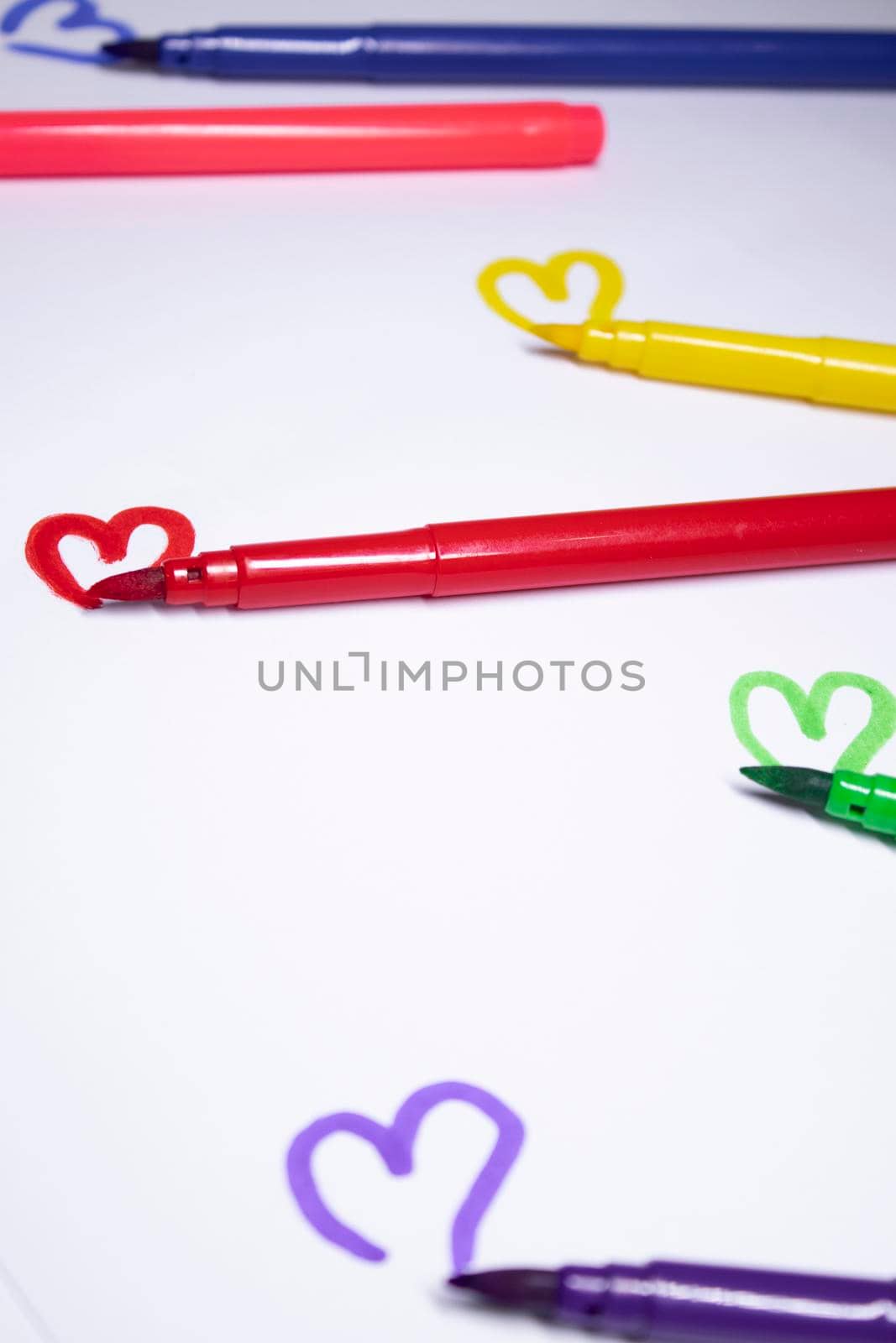 multicoloured felt-tip pen with a painted heart next to it. stationery concept. copy space. isolated. High quality photo