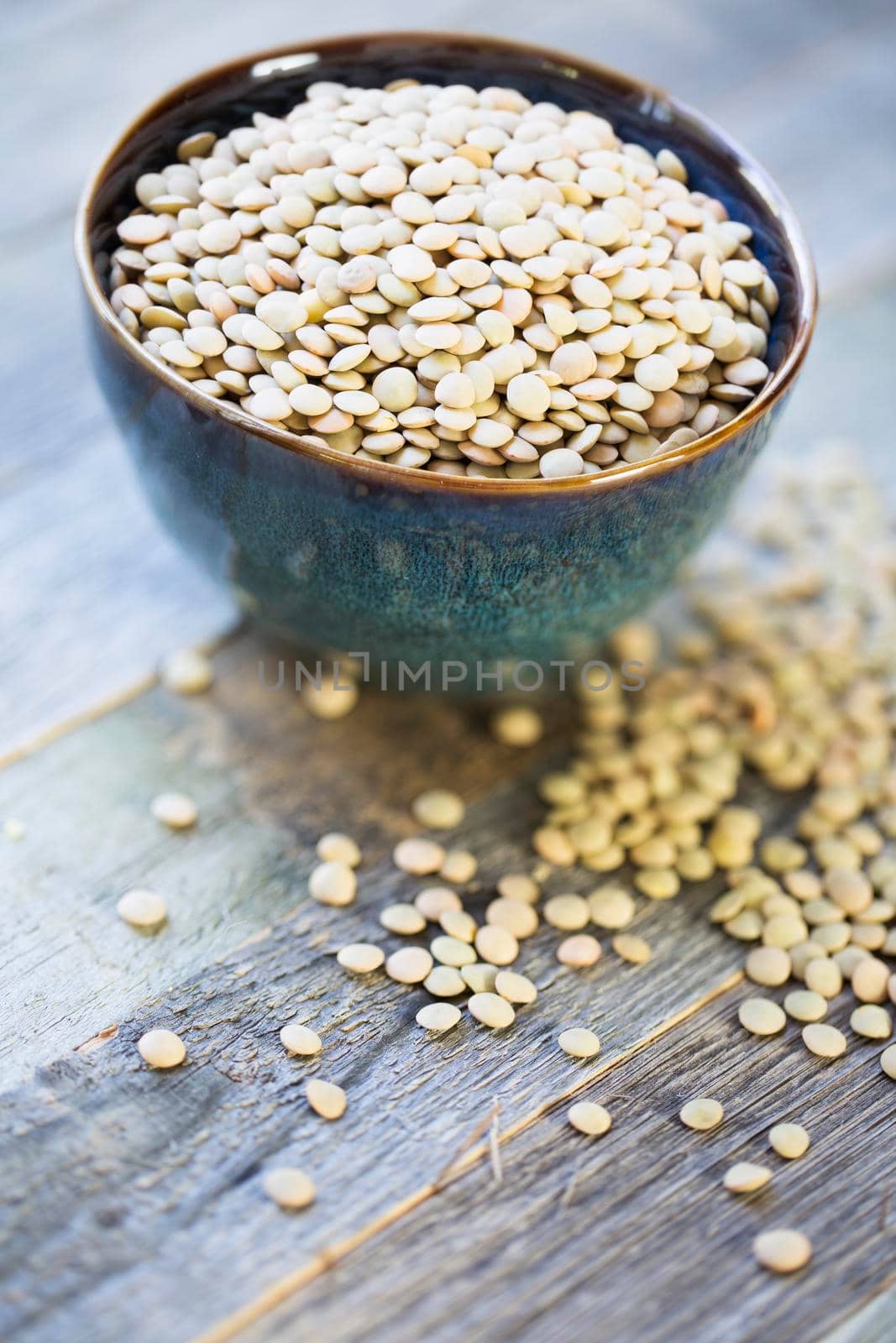 Fresh dried green lentils in ceramic bowl set on wooden table