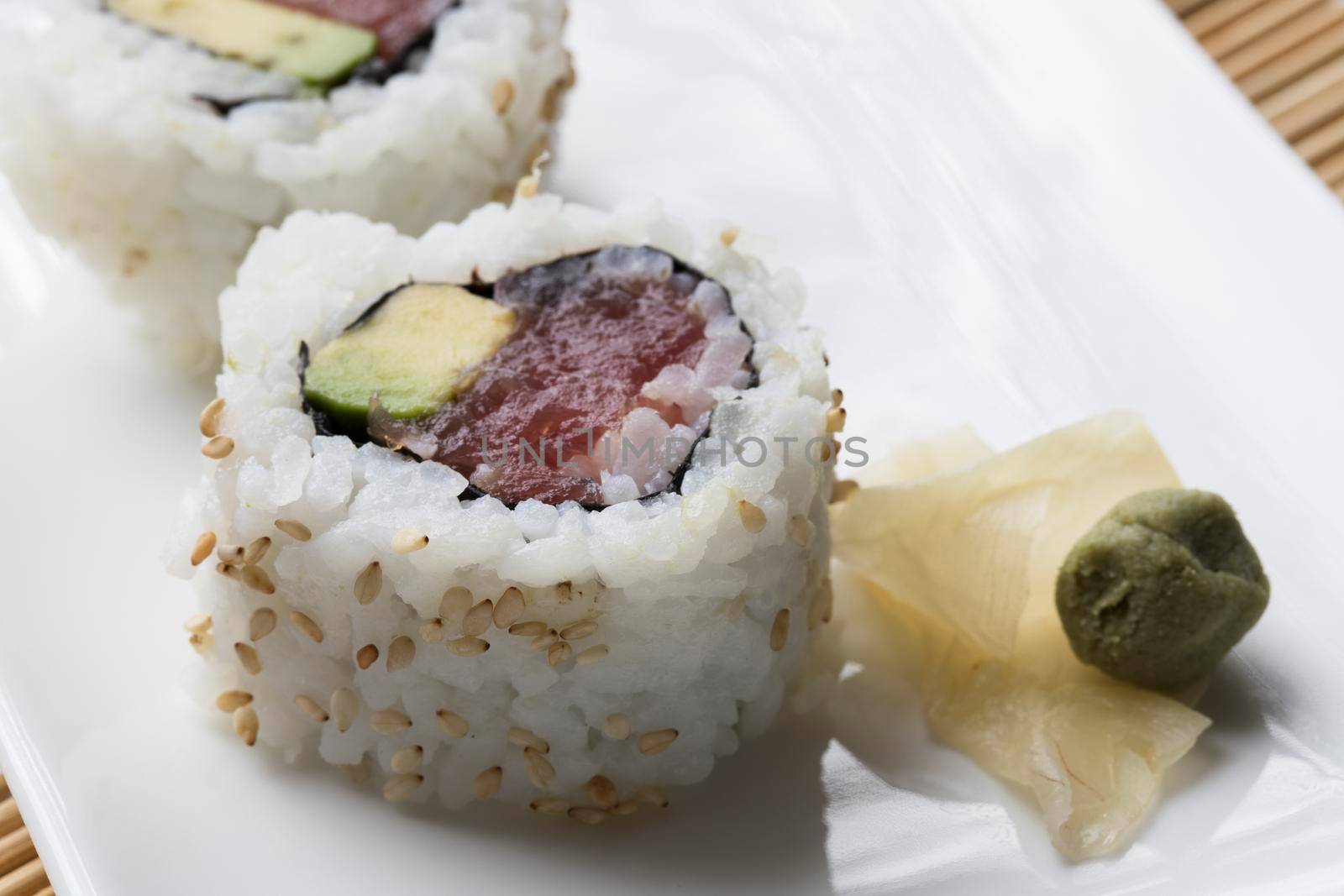 Fresh tuna and avocado uramaki sushi roll with wasabi and pickled ginger.