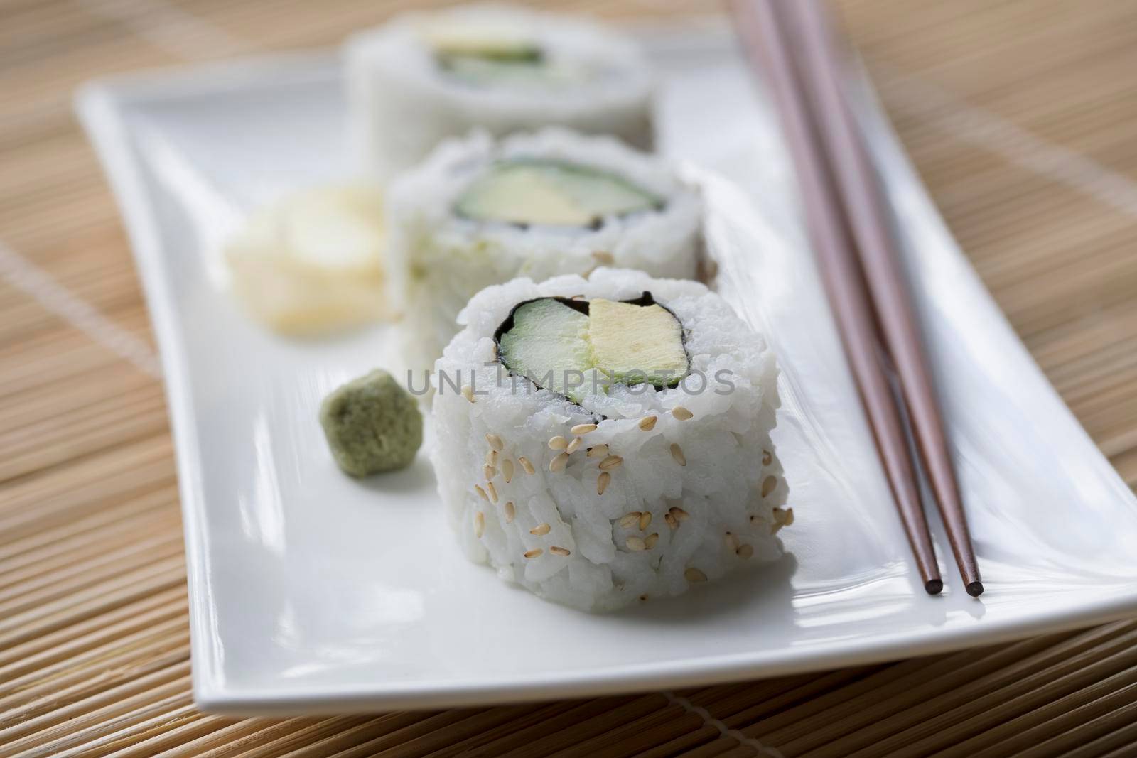 Vegan cucumber and avocado uramaki sushi rolls with wasabi and pickled ginger.