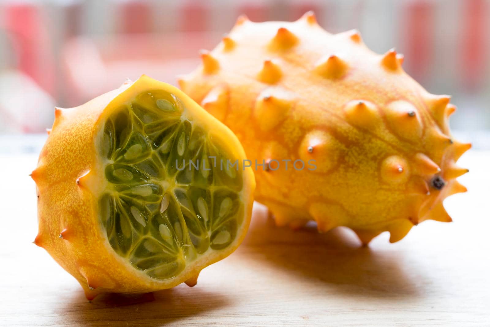 Whole and cut kiwano fruit on cutting board.