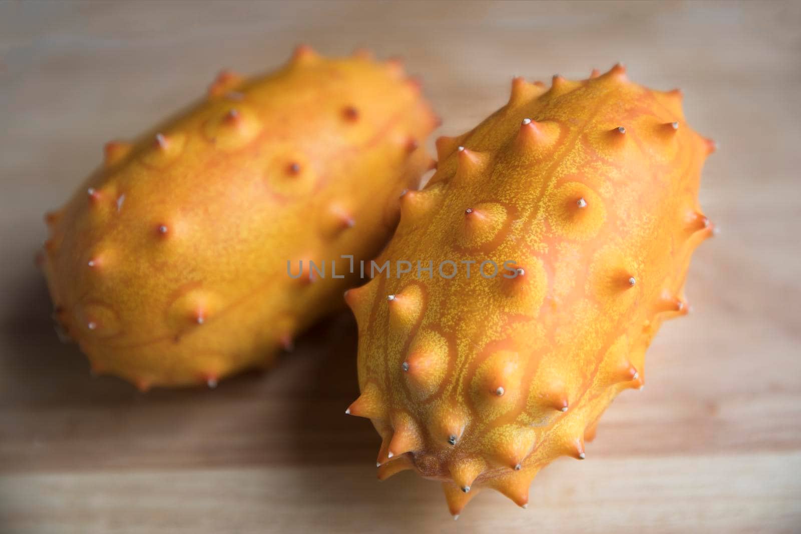 Two whole kiwano fruits on wodden surface