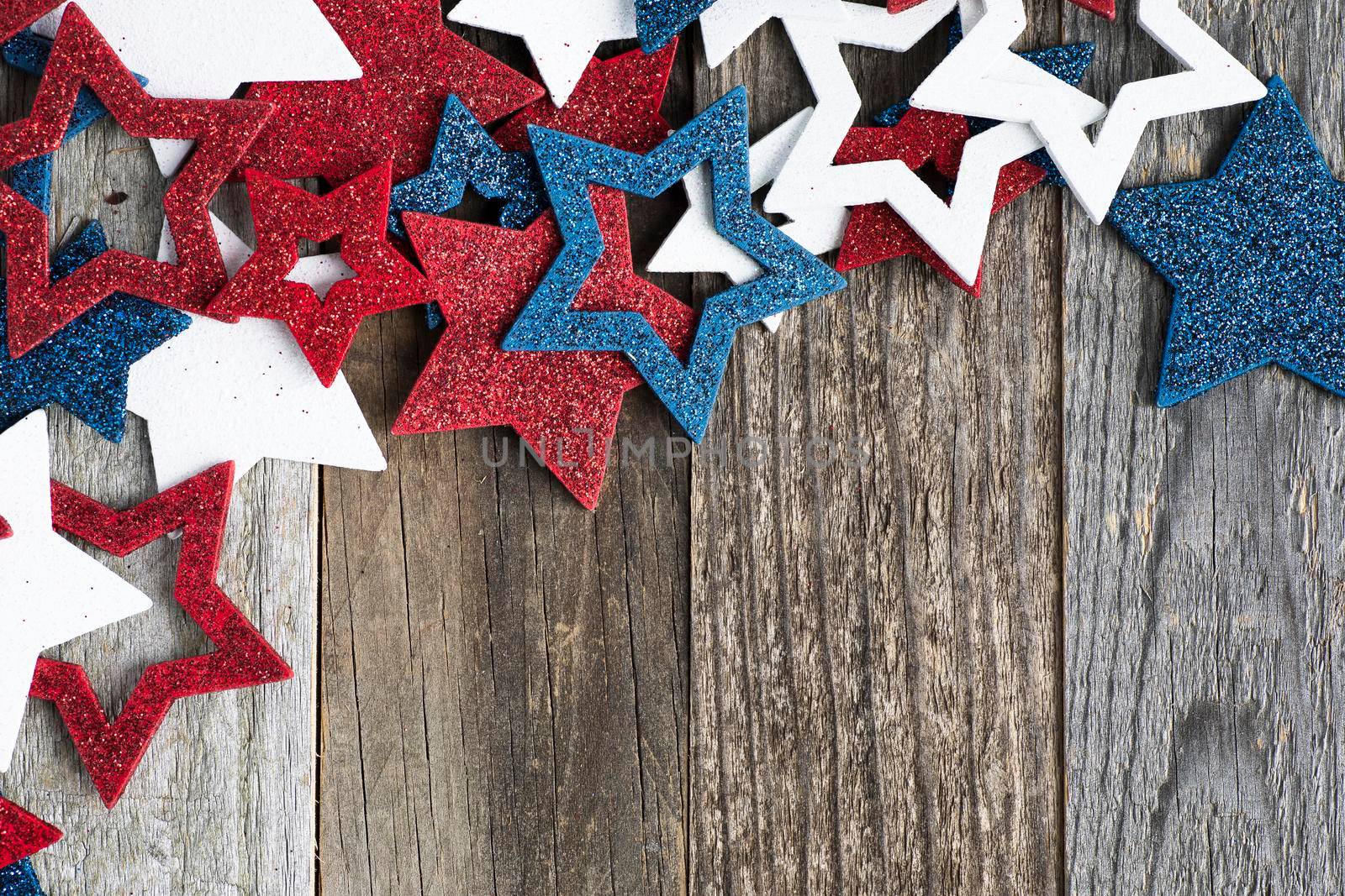 Red white and blue glittery star decorations on wooden surface with copy space.