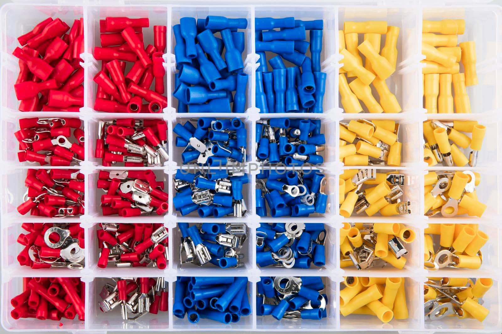 Yellow, blue and red electric terminal connectors organized in plastic container.