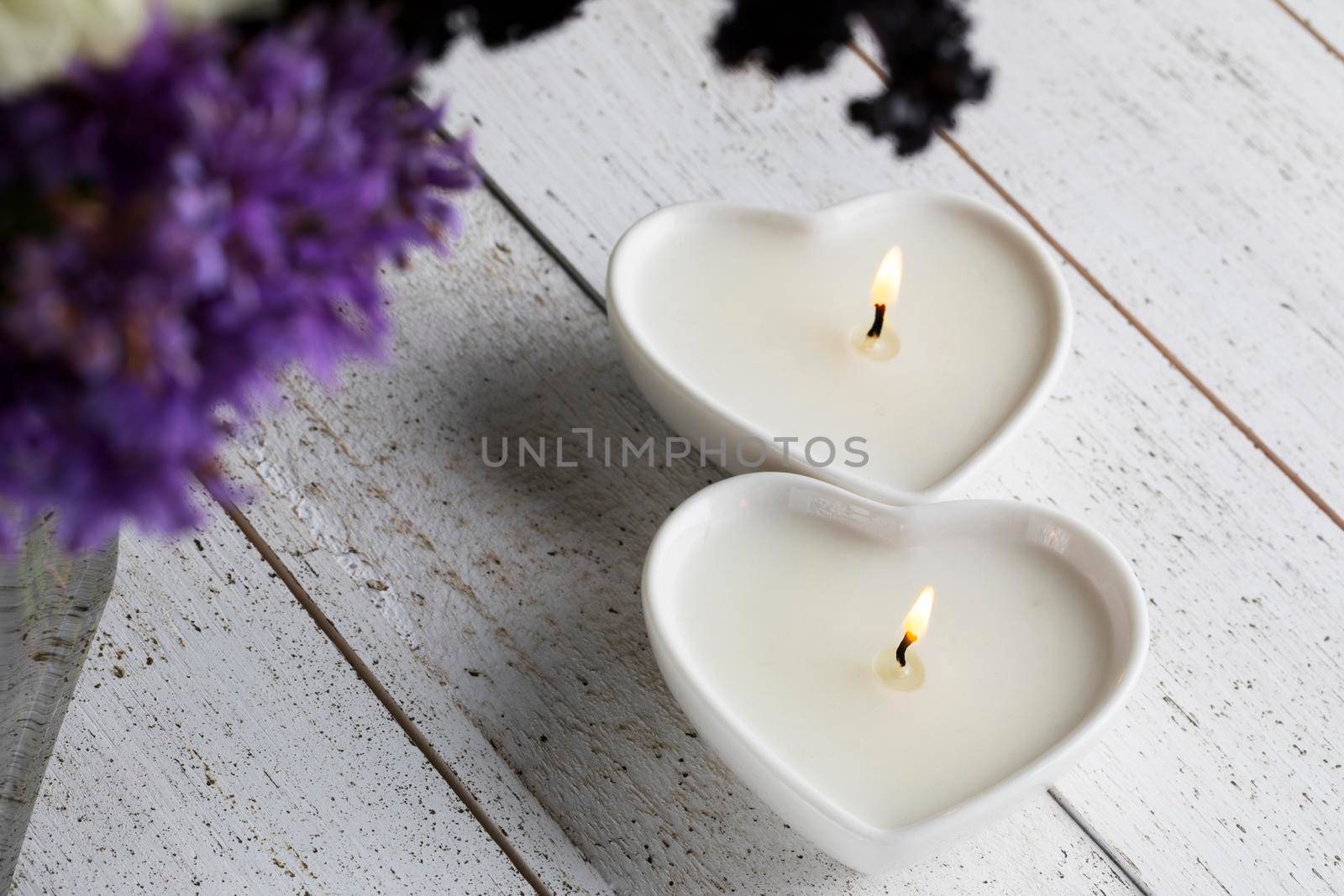 Two peaceful heart shaped candles on a white wood table