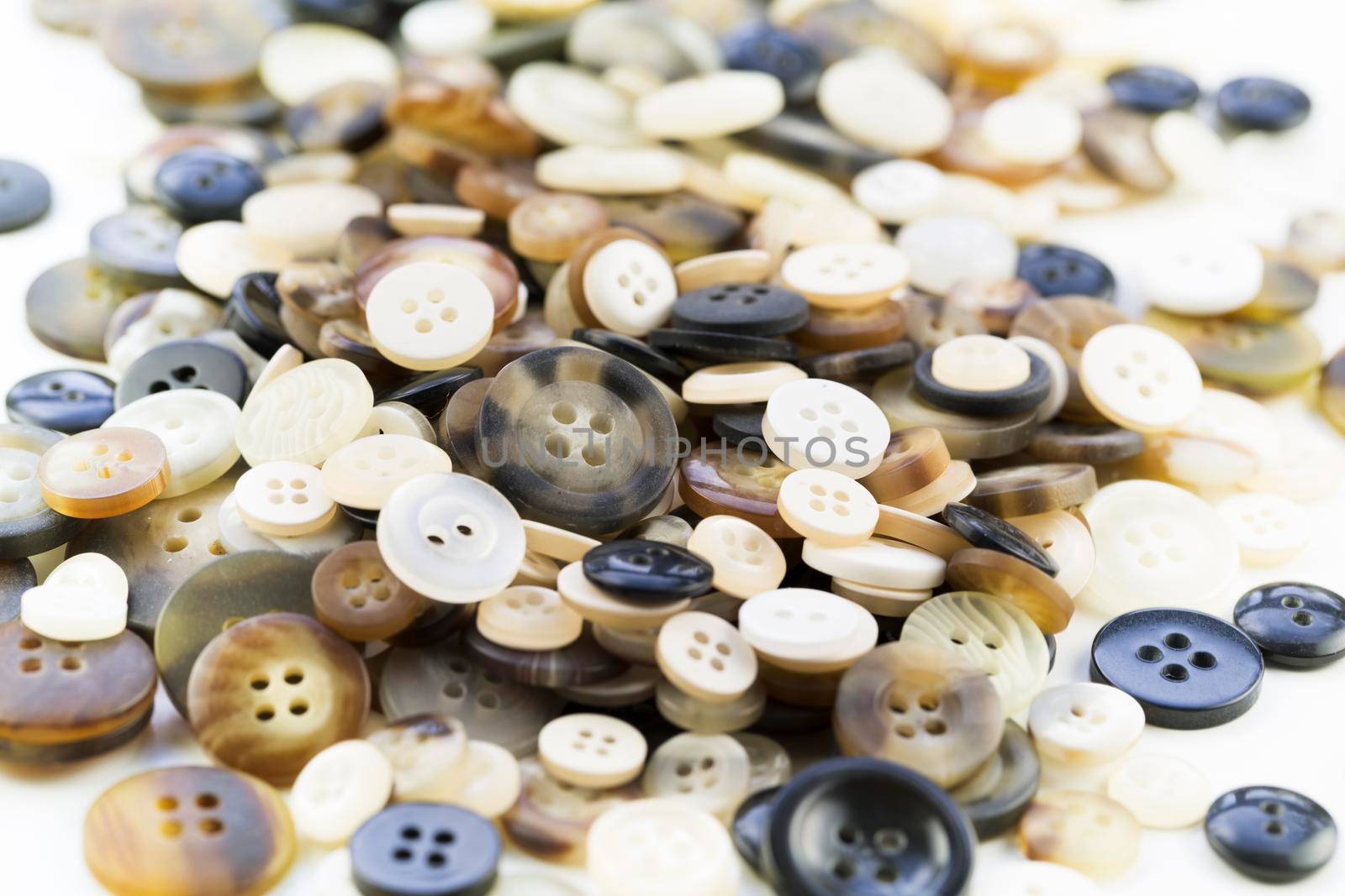 Pile of buttons in browns, white and black tones.