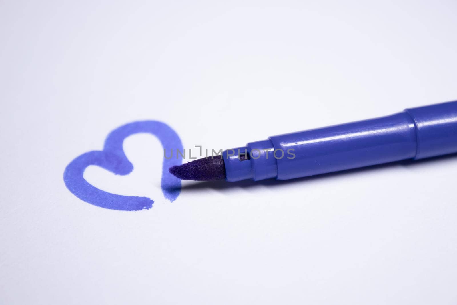 blue felt-tip pen with a painted heart next to it. stationery concept. copy space. isolated. High quality photo