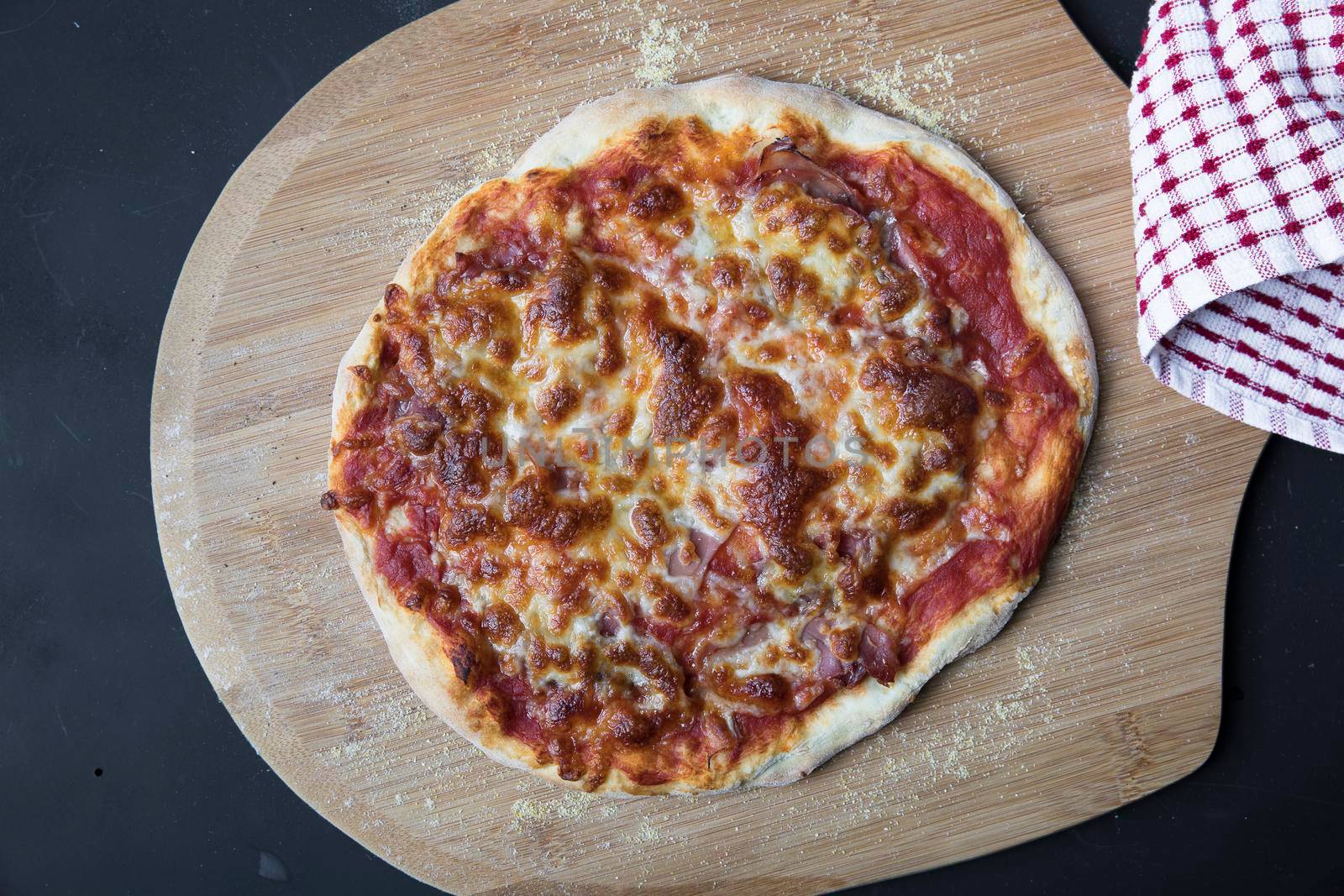 Whole cheese pizza fresh from the oven on pizza peel.