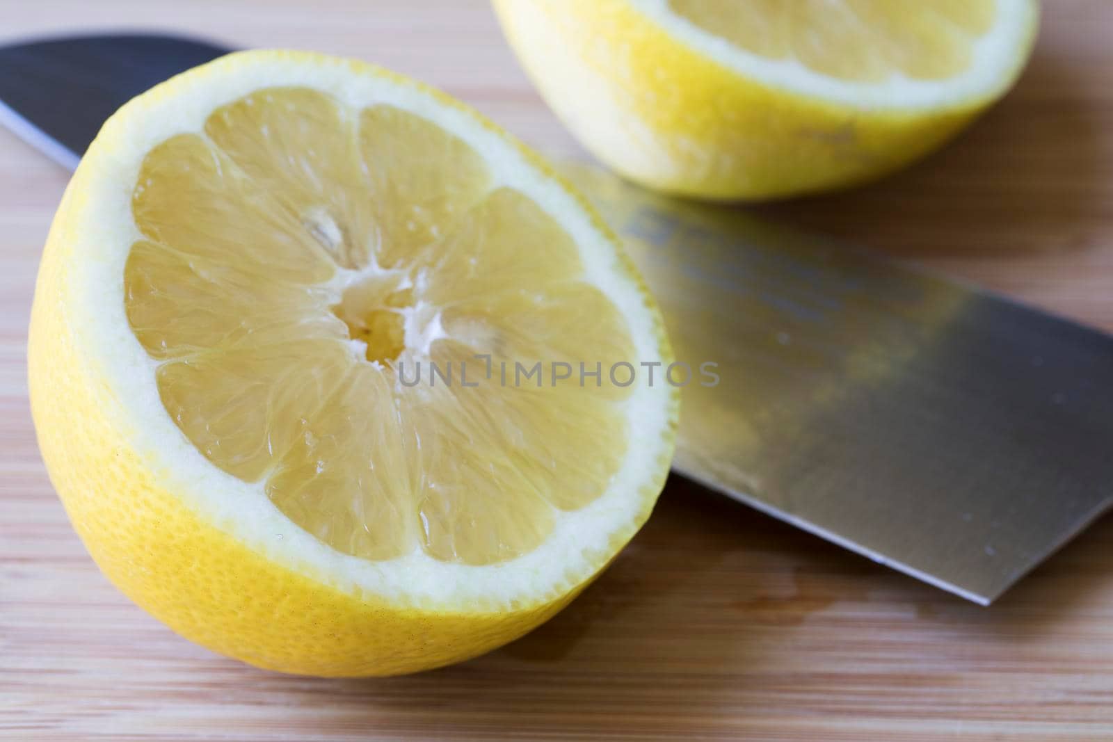 Lemon sliced in half with knife on cutting surface