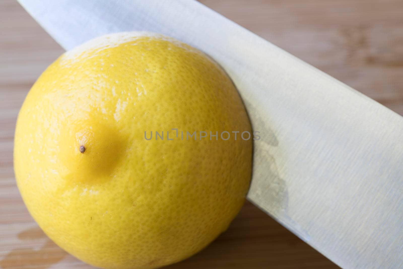 Fresh lemon with knife blade slicing in half