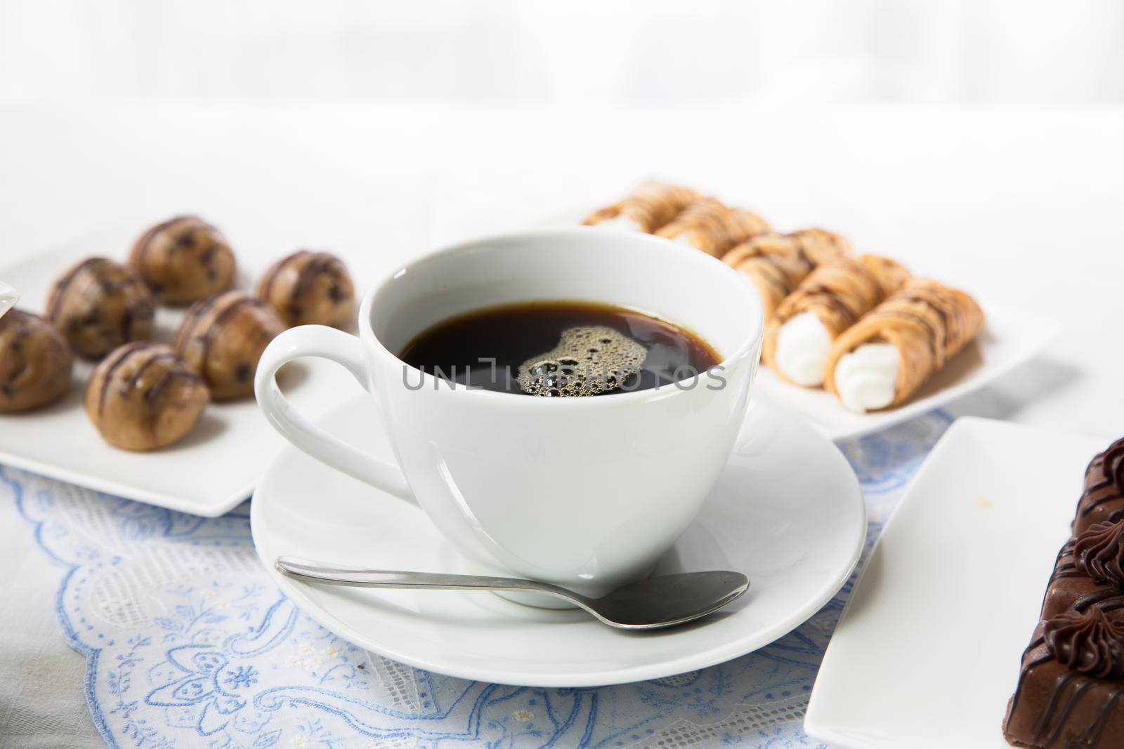 Cup of fresh coffee with chocolates and pastries