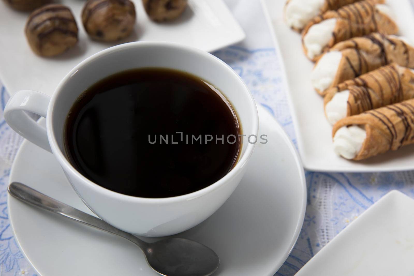 Cup of fresh coffee with chocolates and pastries