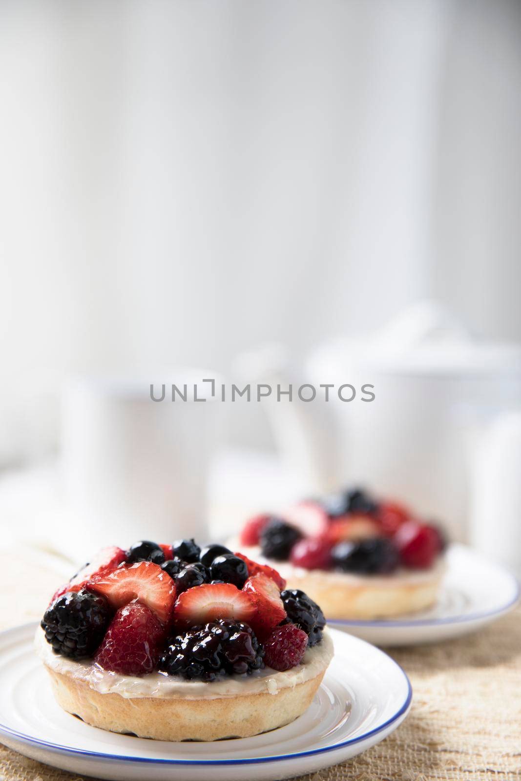 Two mixed berry tarts with tea kettle in background