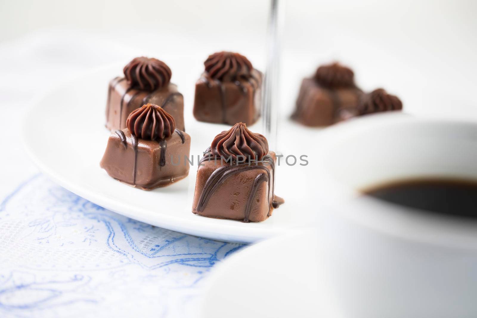 Gourmet chocolates with milk and dark chocolate with coffee out of focus in foreground.