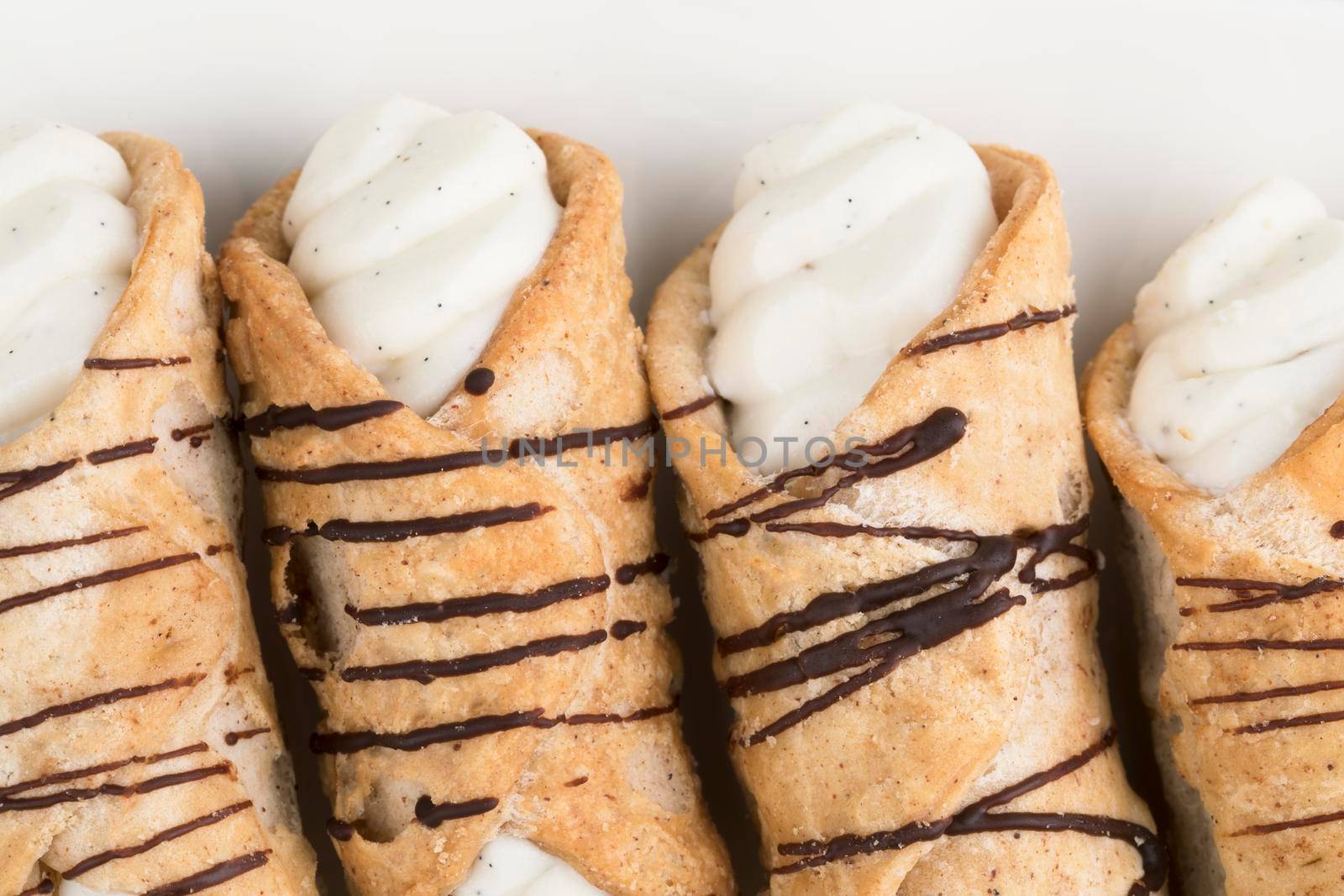 Close up of pastries stuffed with sweet cream and drizzled with chocolate, viewed from avove