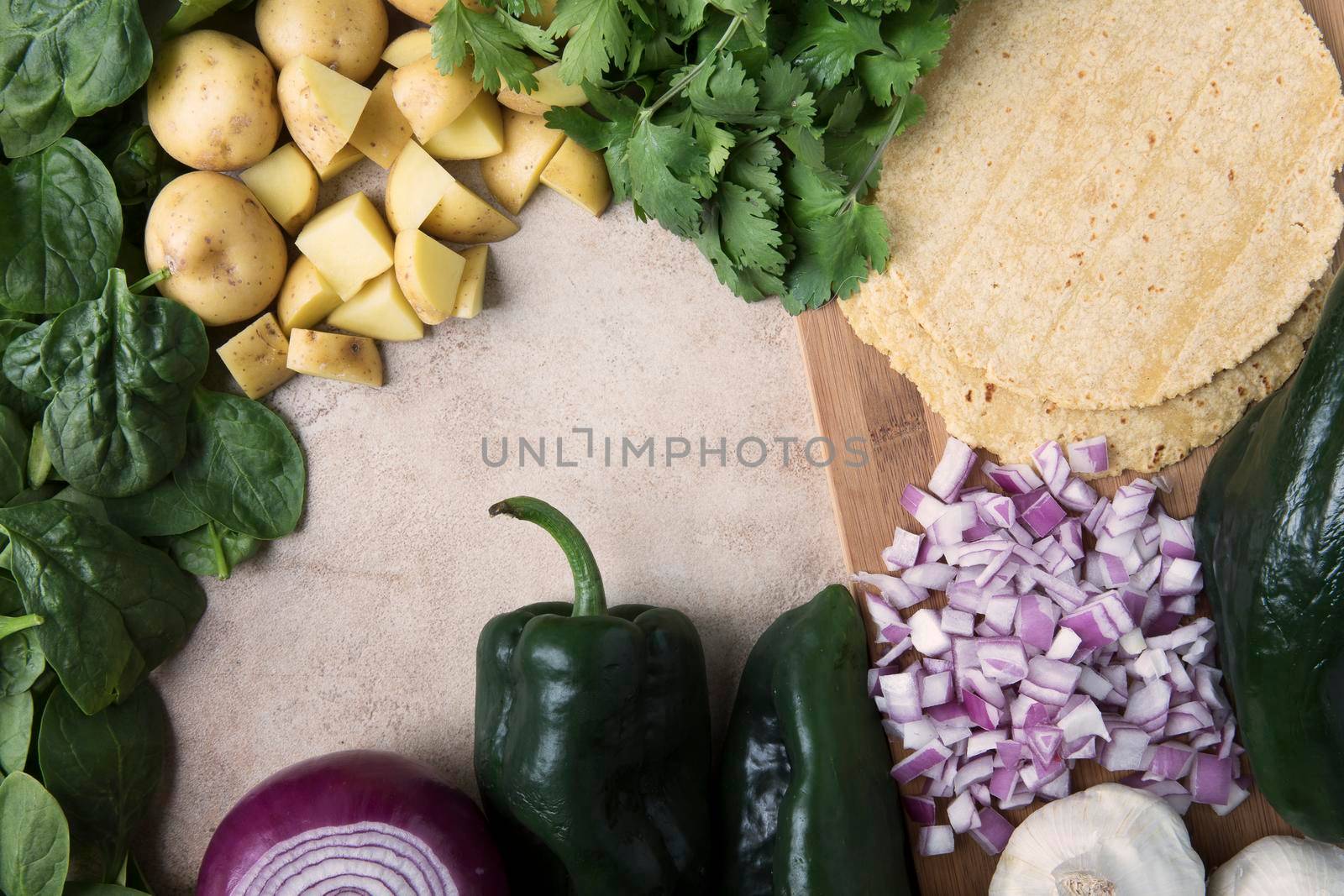 Red onions, poblano peppers, corn tortillas, potatoes, spinach and cilantro; ingredients for vegan tacos.