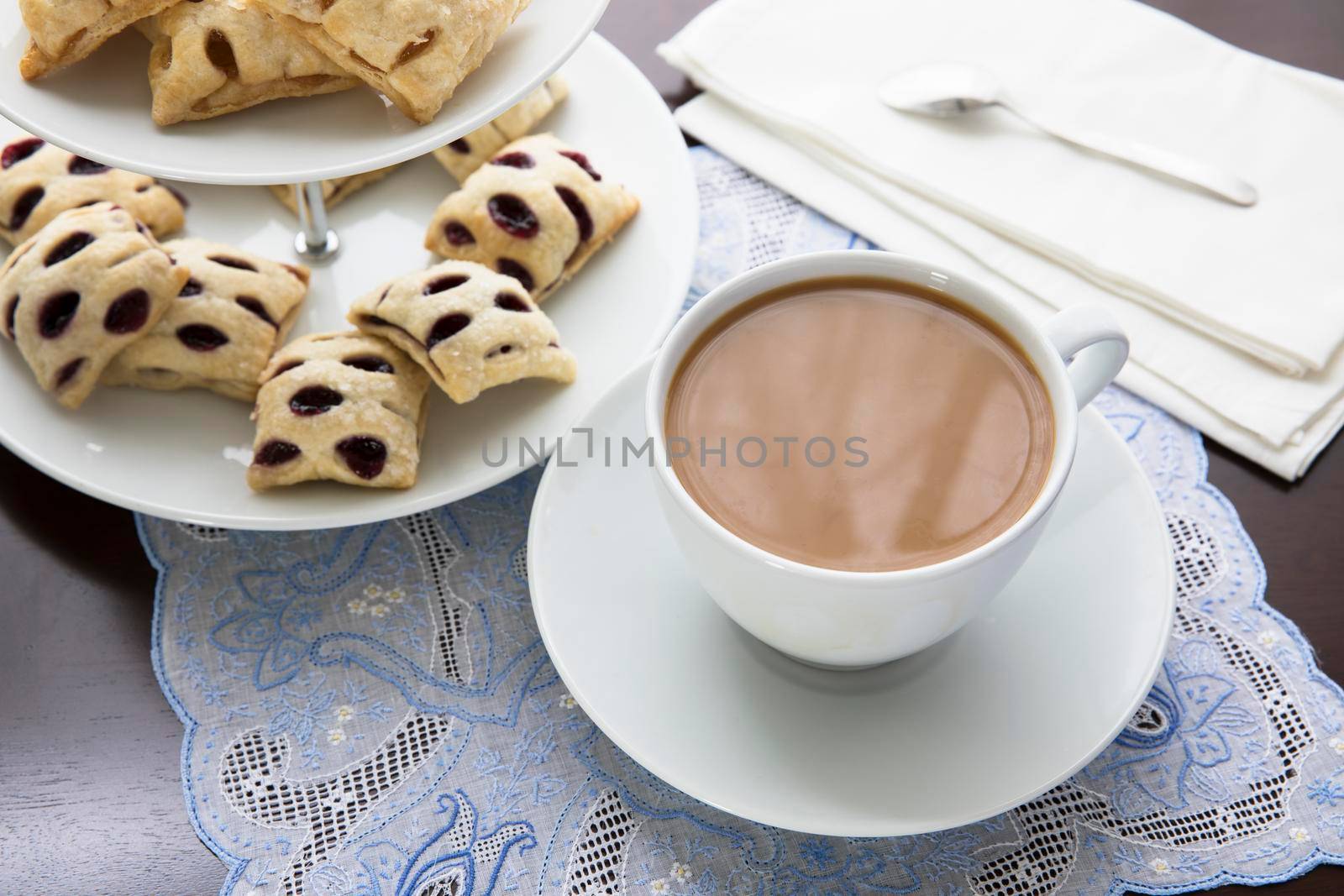 Cup of coffee or tea with fruit filled mini strudels on a pastry stand.