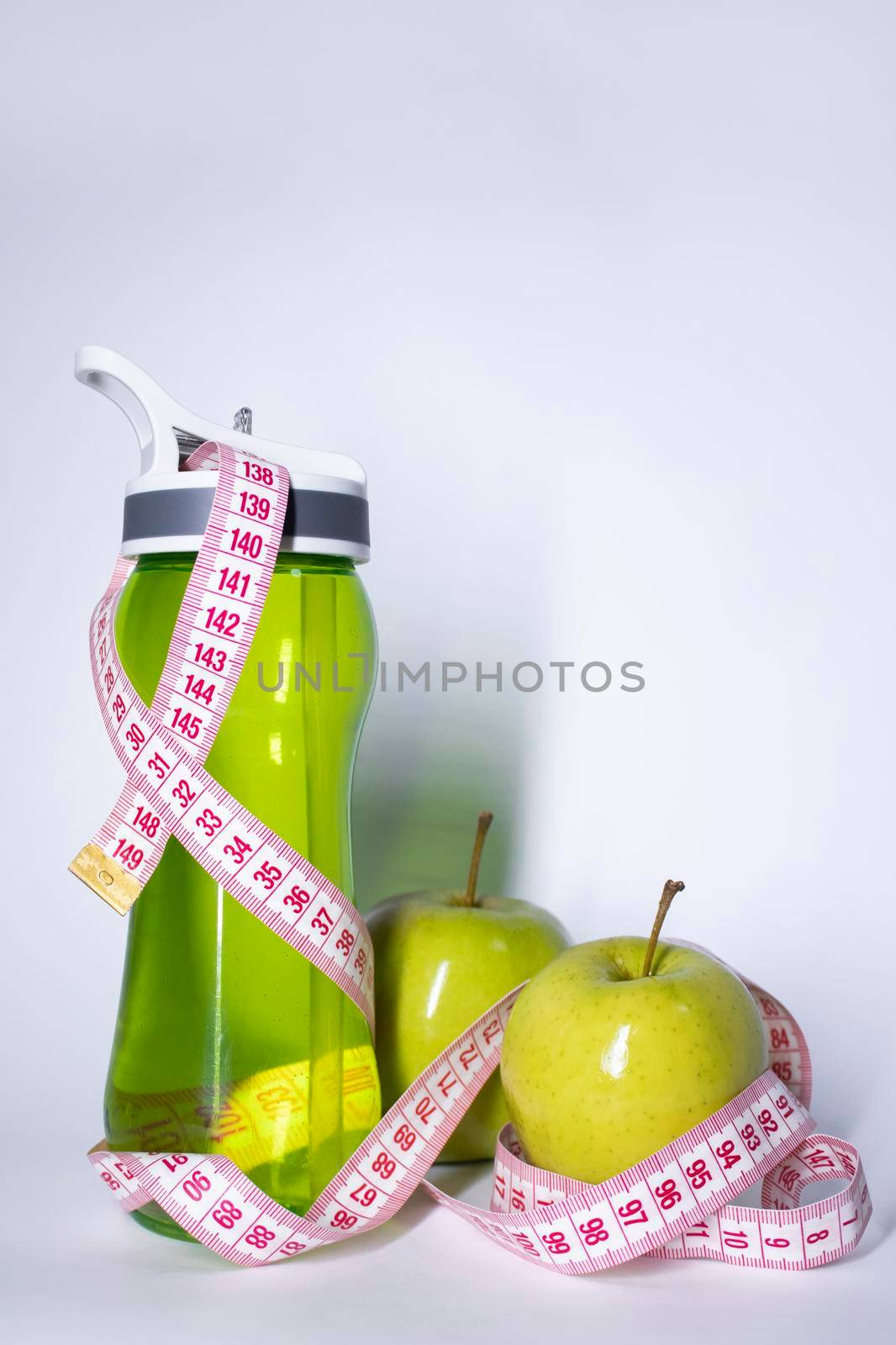 Red measuring tape over green sport bottle and green apple. Diet and Healthy life, loss weight, sport concept. Top view. Copy space. Isolated. White background. High quality photo