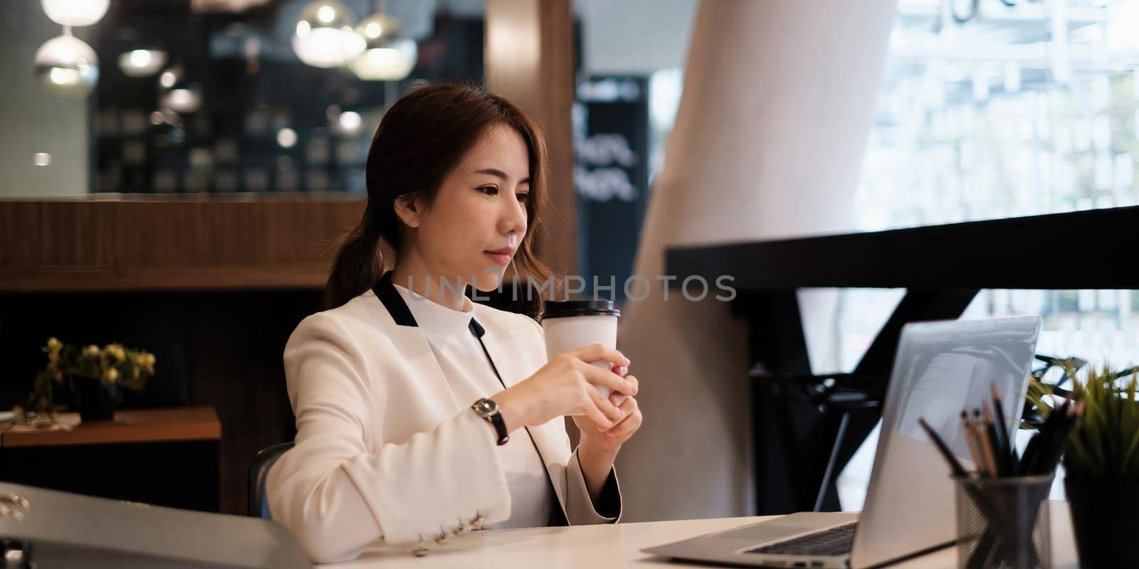 Female executive thinking over working schedule for employee writing report into digital laptop in coworking space