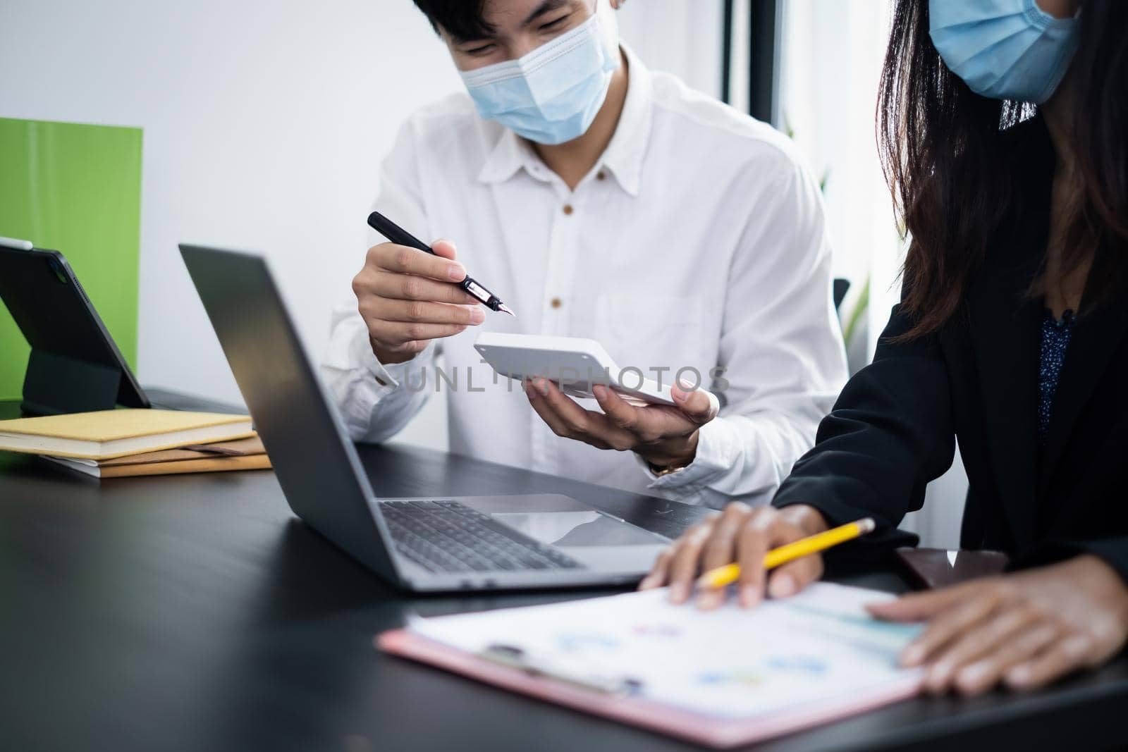 Business People wear mask at meeting to discuss and brainstorming the financial report paperwork in home office. Financial advisor teamwork and accounting concept.
