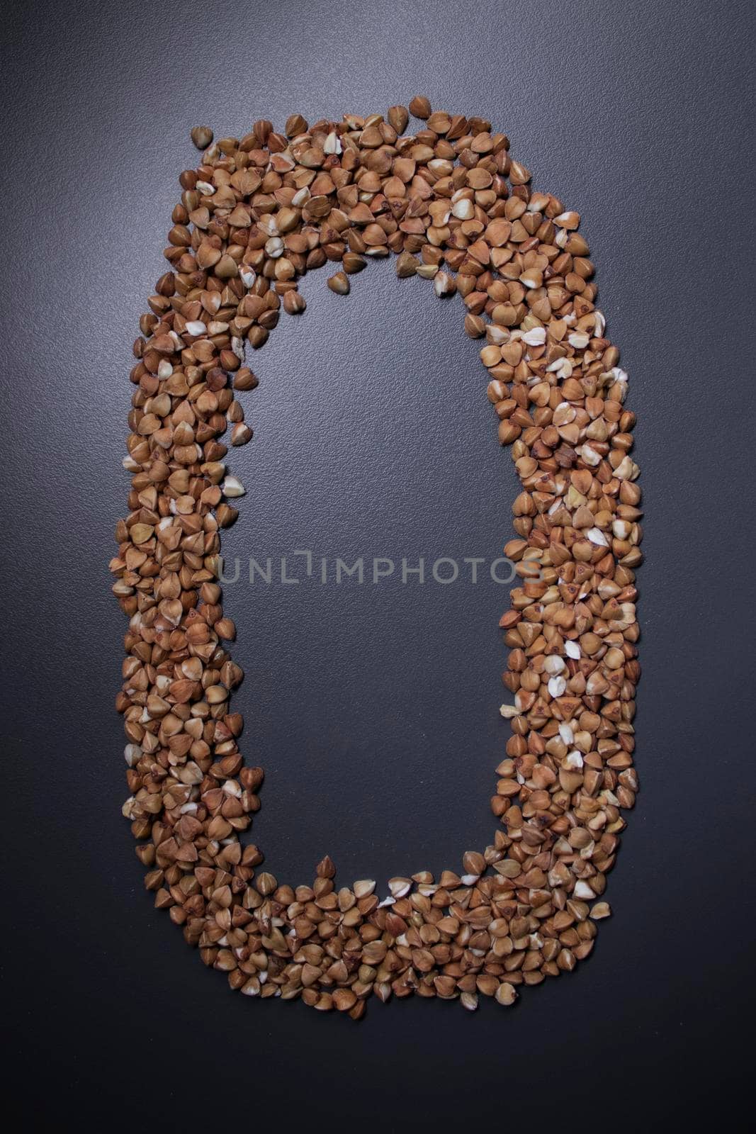 Letter 'o' written with buckwheat On gray background, top view, copy space. Food supplies crisis, food donation on quarantine isolation period