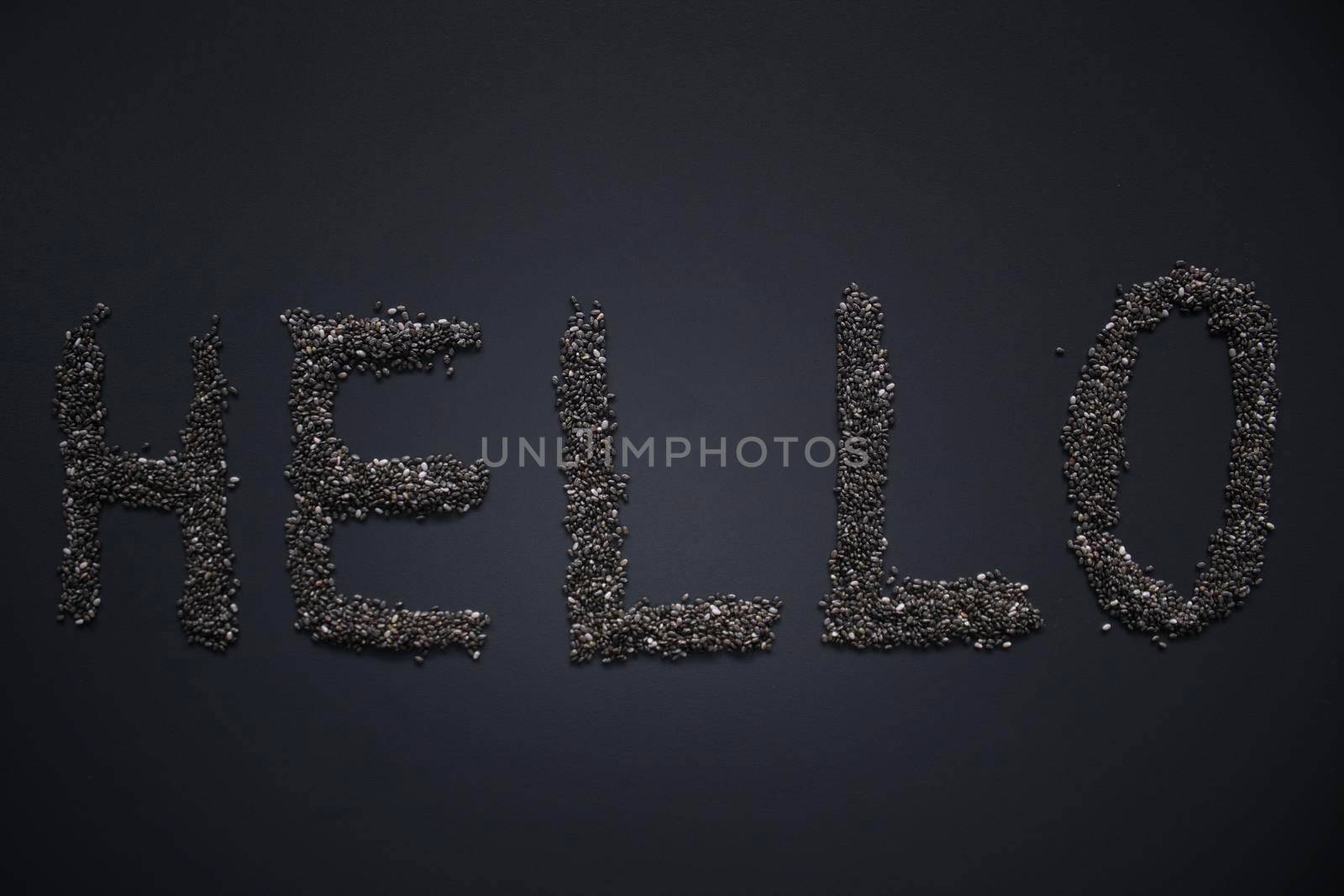 Word 'HELLO' written with chia seeds on gray background, top view, copy space.