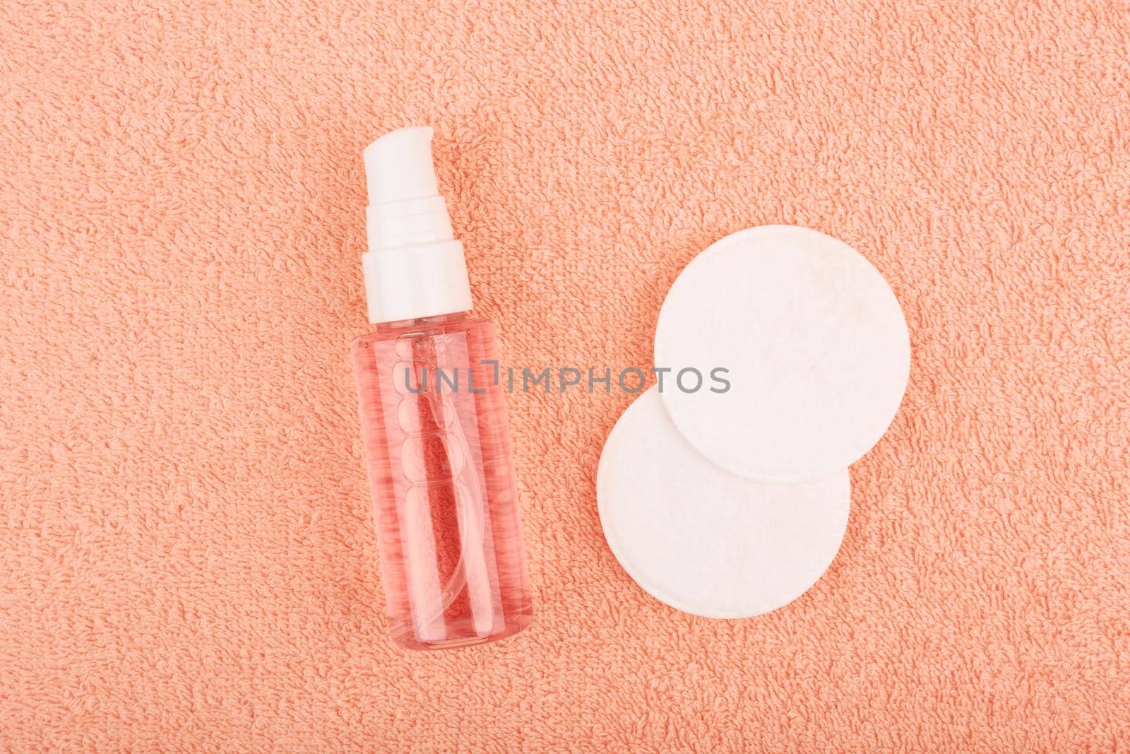 Cleansing foam or gel for make up removing and cotton pads on light orange fleecy towel. Concept of skin care and make up removing