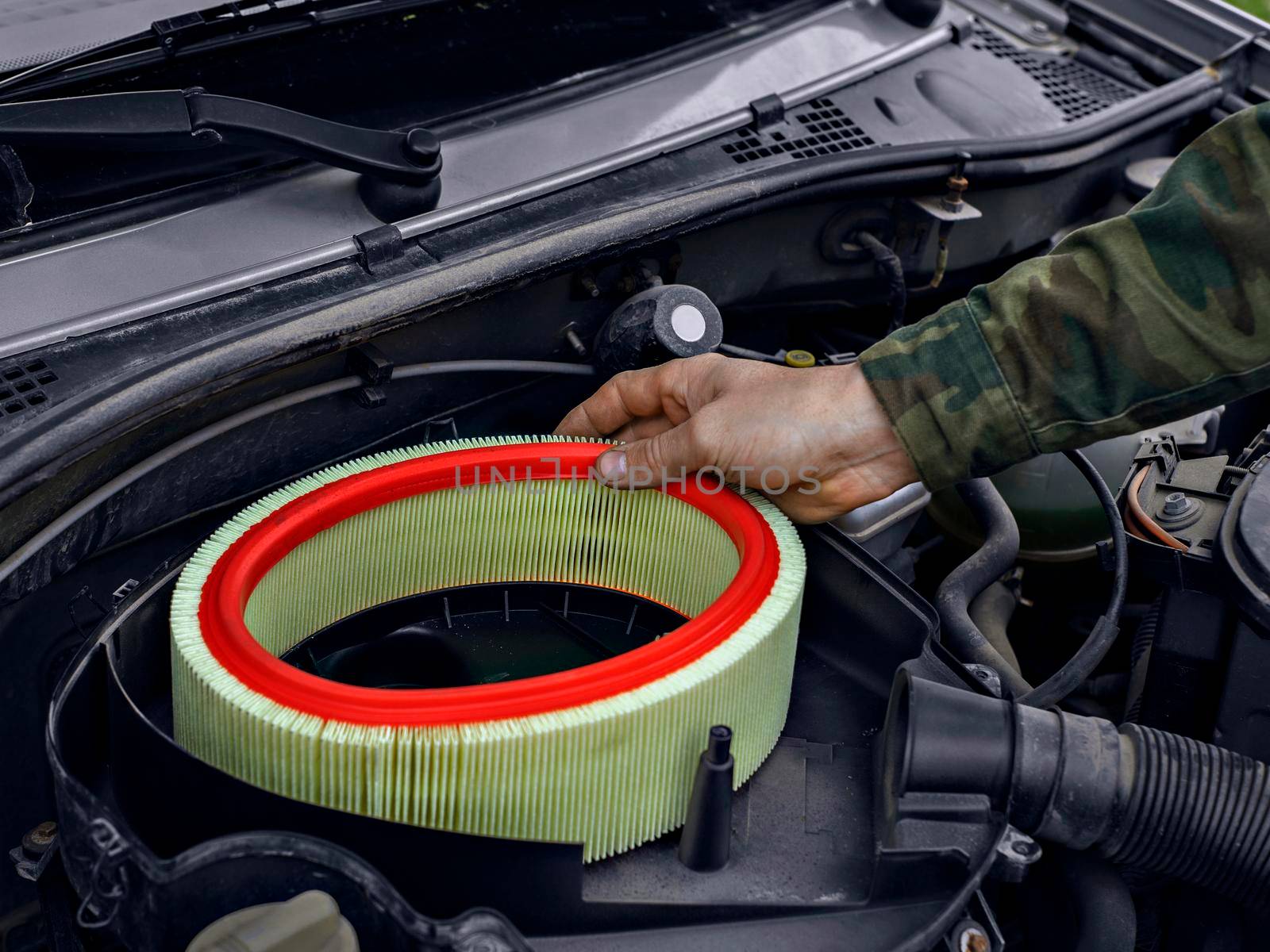 Man replaced air filter on engine of car.