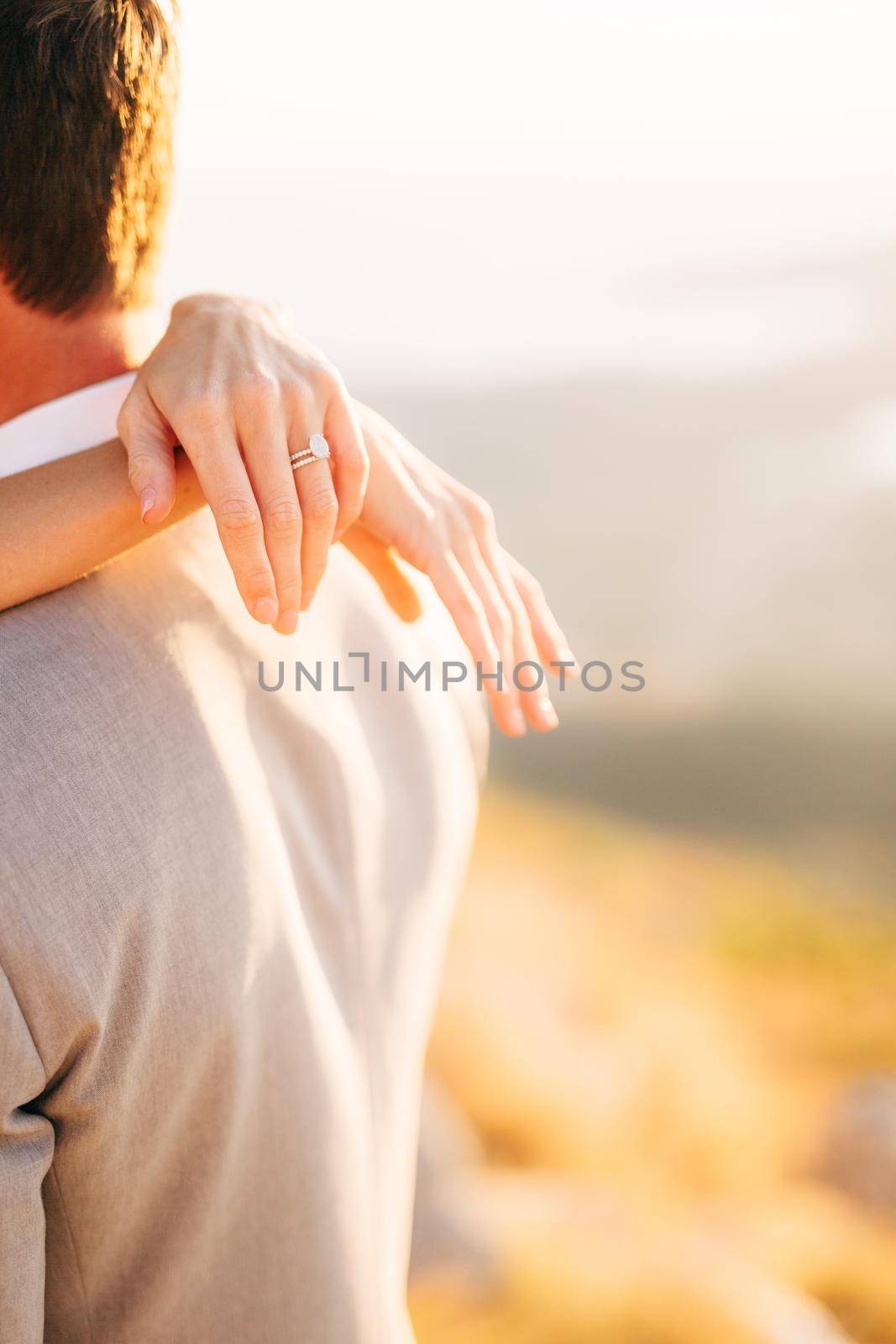 The bride hugs the groom, the bride's hands with the wedding ring on the groom's shoulders, close-up . High quality photo
