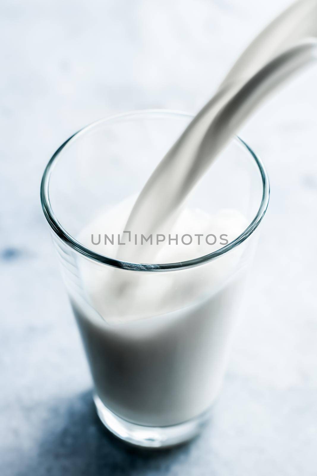 Dairy, healthy nutrition and breakfast concept - World Milk Day, pouring into glass on marble table