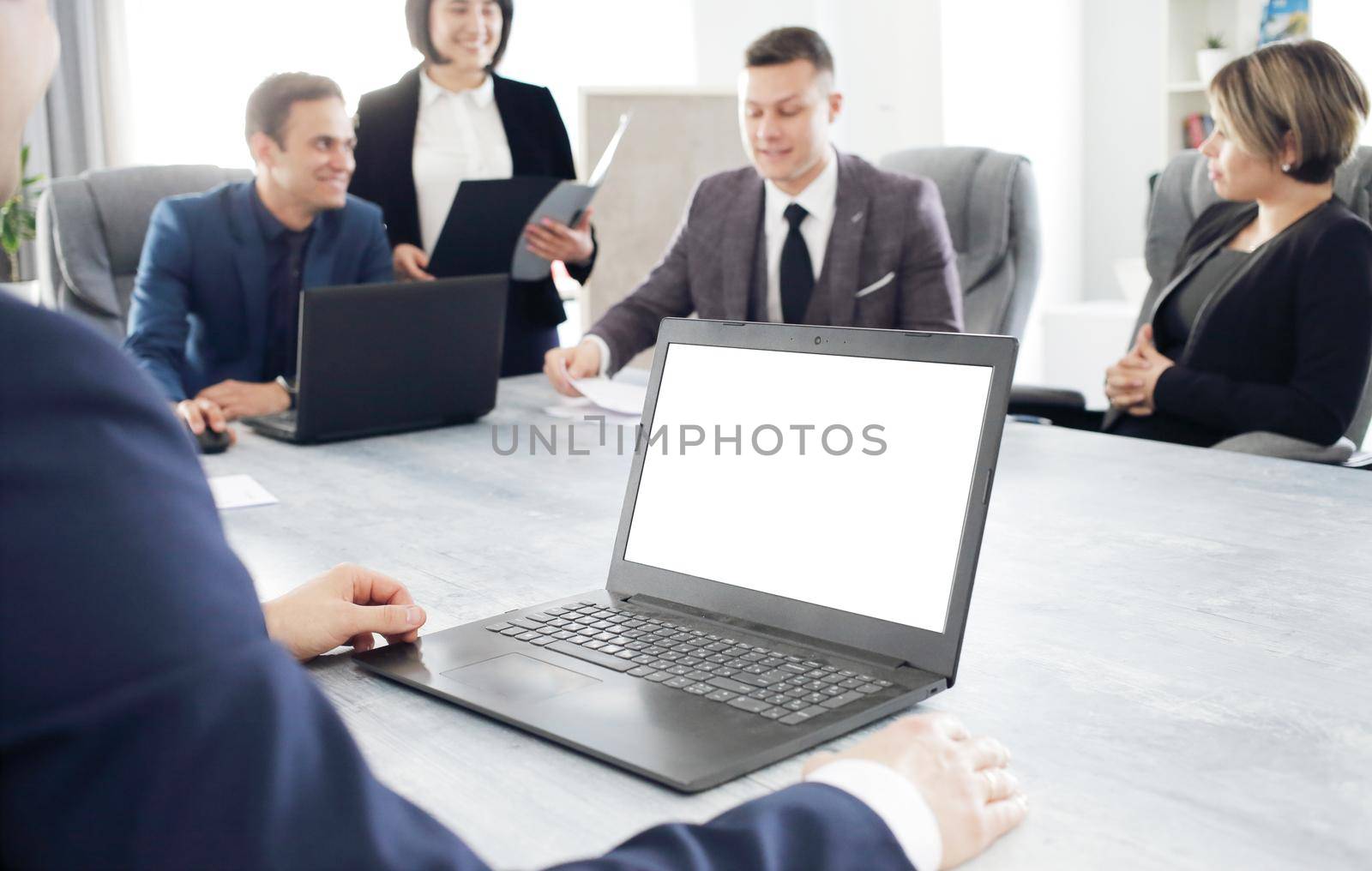 Laptop against the background of a group of young business people in the office discussing a work idea together by selinsmo