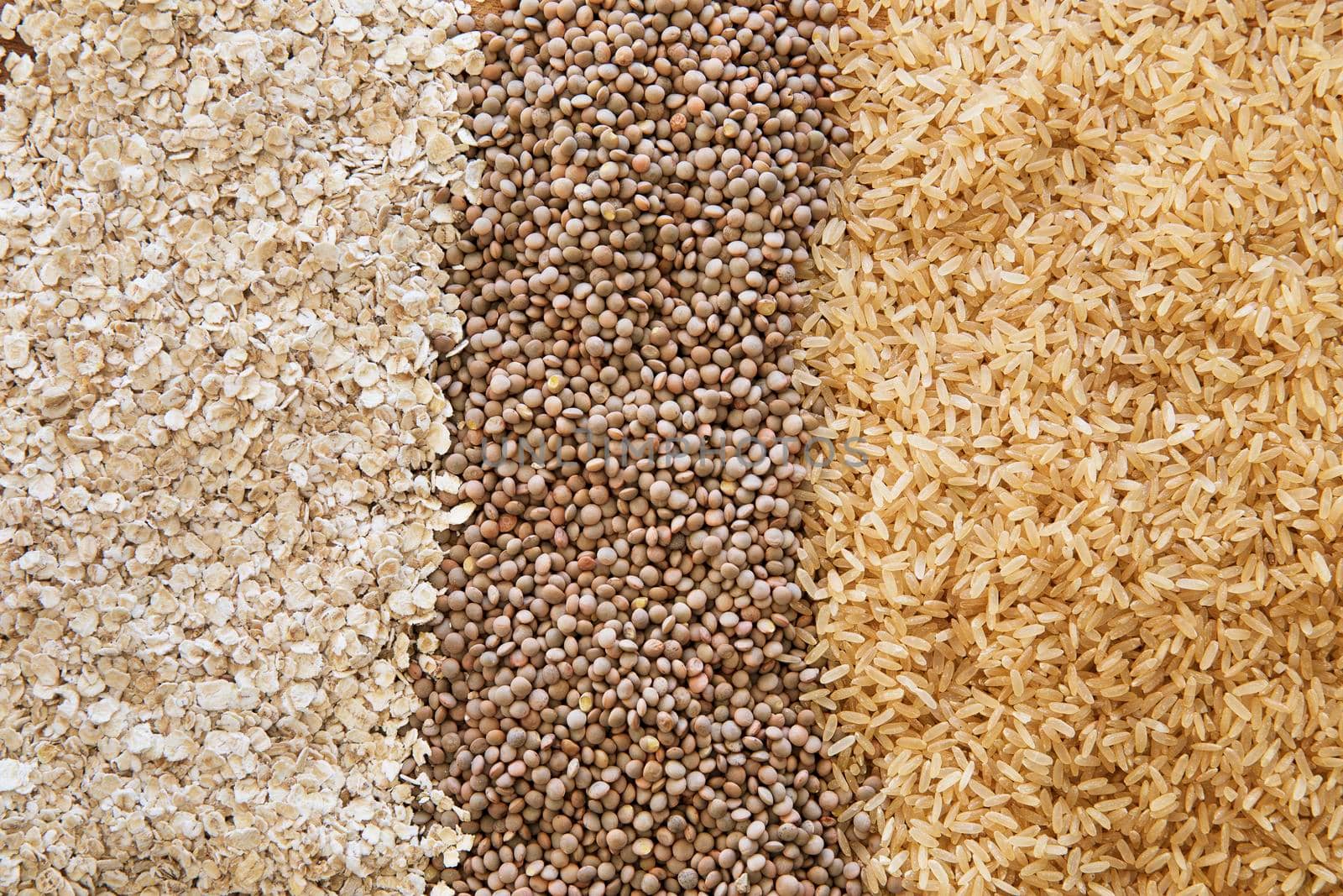 Three healthy products: brown rice, lentils, and oats as a food background.