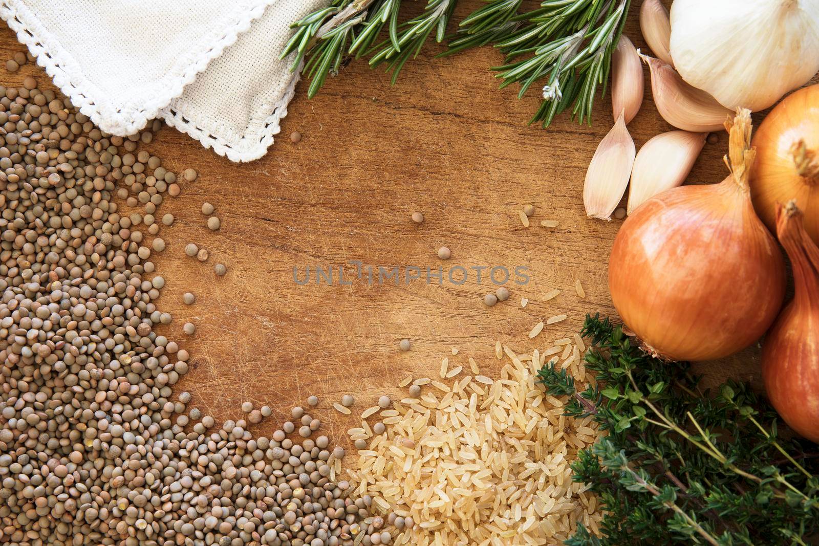 Healthy food frame with fresh vegetables, herbs and grains on rustic wooden background viewed from above.