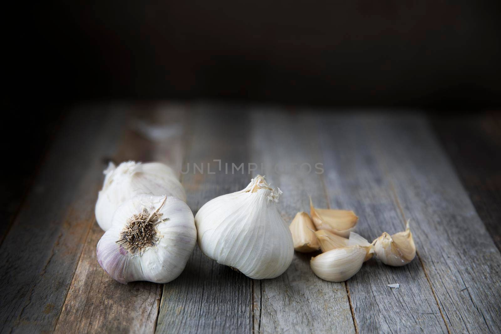 Garlic heads and cloves on wooden table with copy space.