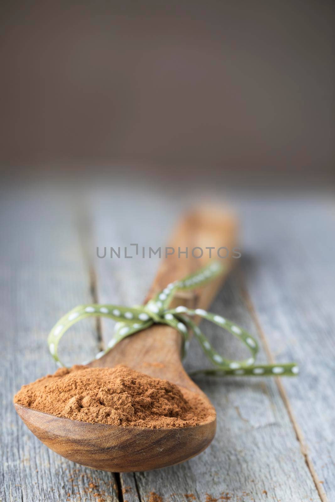 Ground cinnamon in wooden spoon, vertical orientation with copy space.