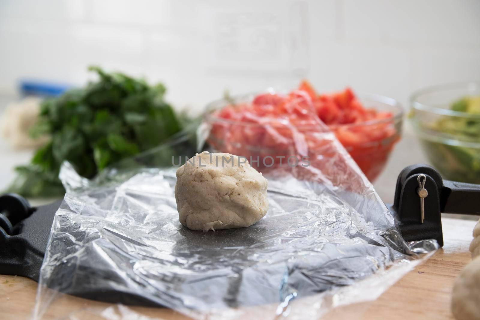 Ball of masa harina tortilla dough on piece of plastic on tortilla press.