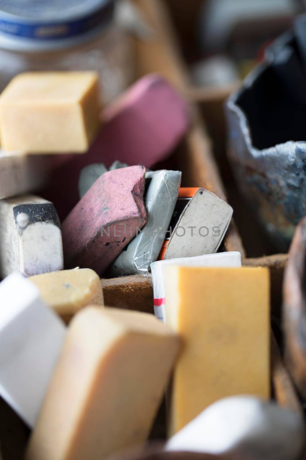 Collection of old dirty and used erasers in artist's supply tray.