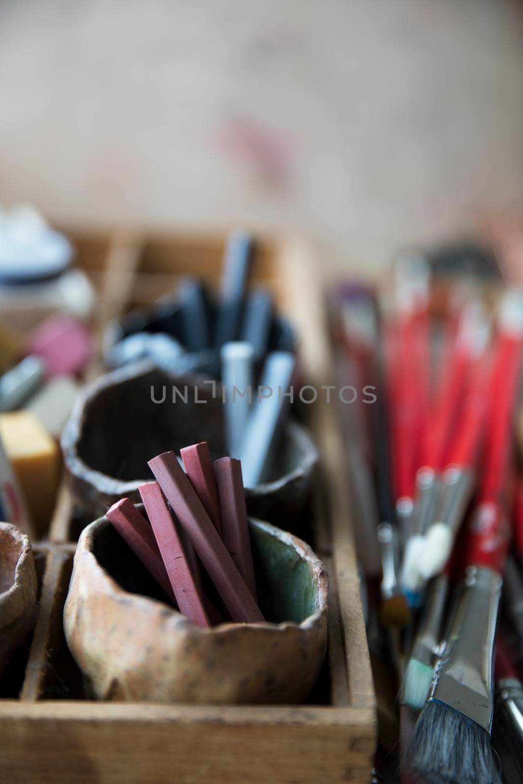 Conte sticks in ceramic pinch pots on artist supply tray with paint brushes
