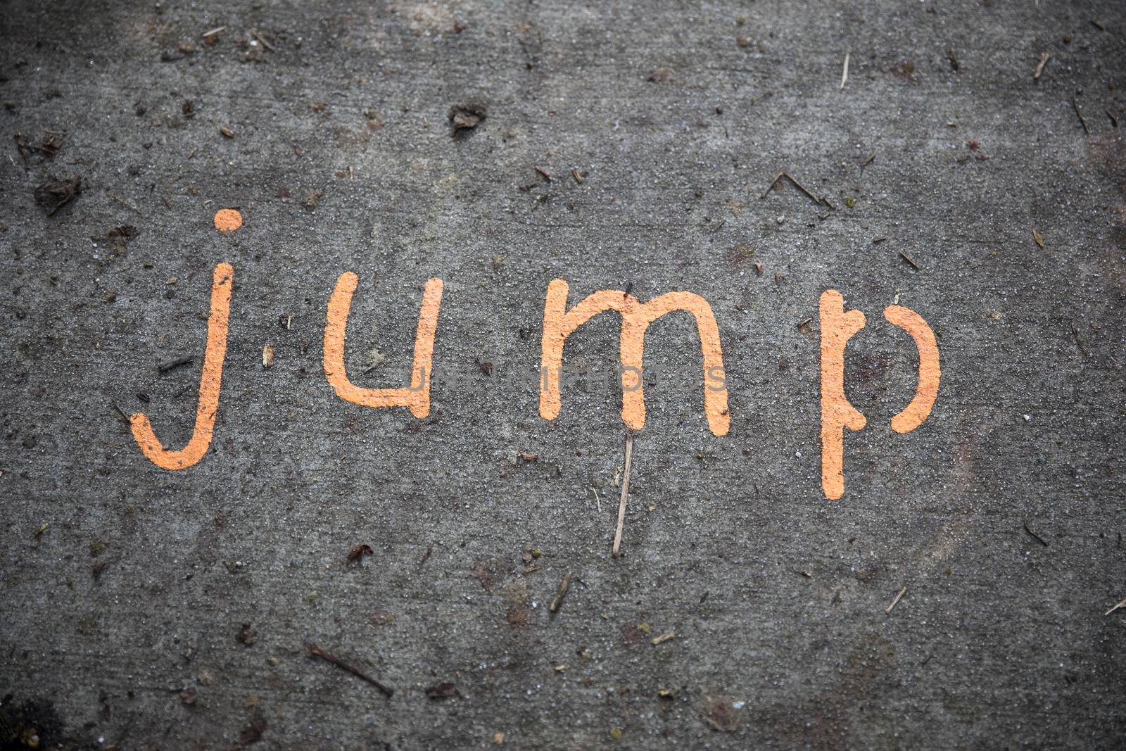 The word jump painted on a concrete sidewalk