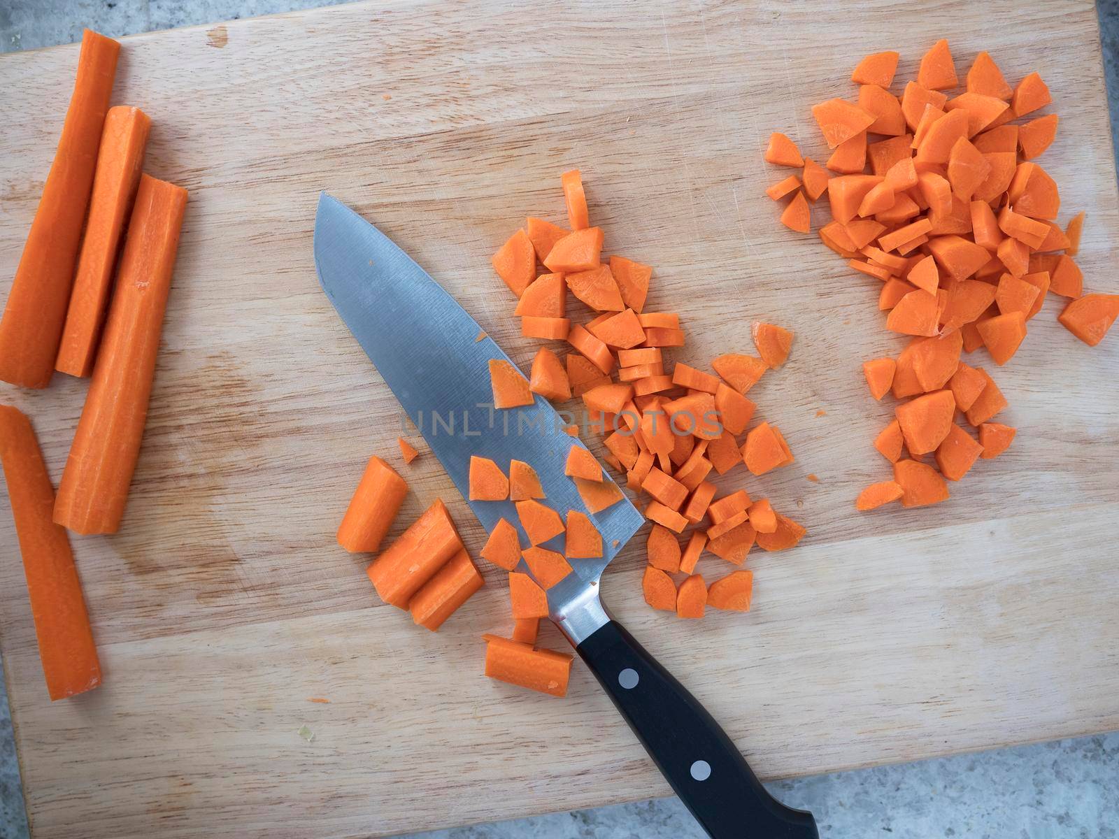 Carrot sticks and chopped carrots on cutting board with knife.