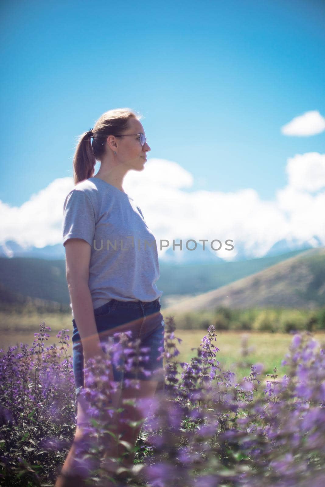 Happy young woman in beautiful wild pink and purple flowers field by rusak