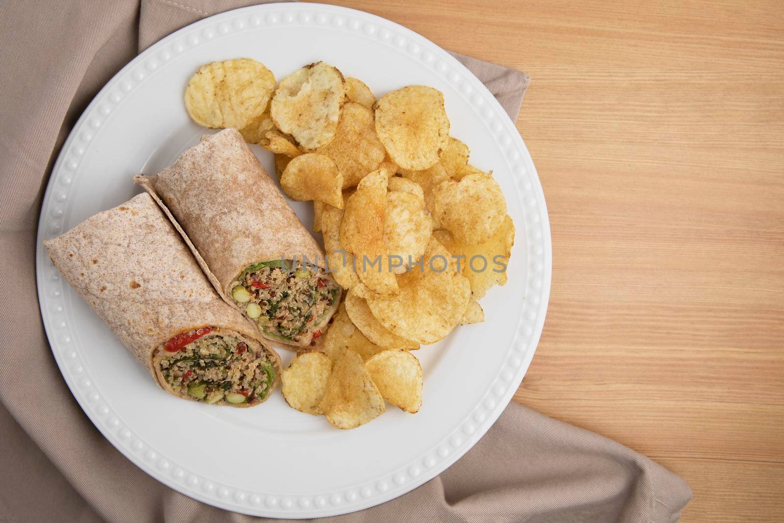 Vegan quinoa wrap served with chips.