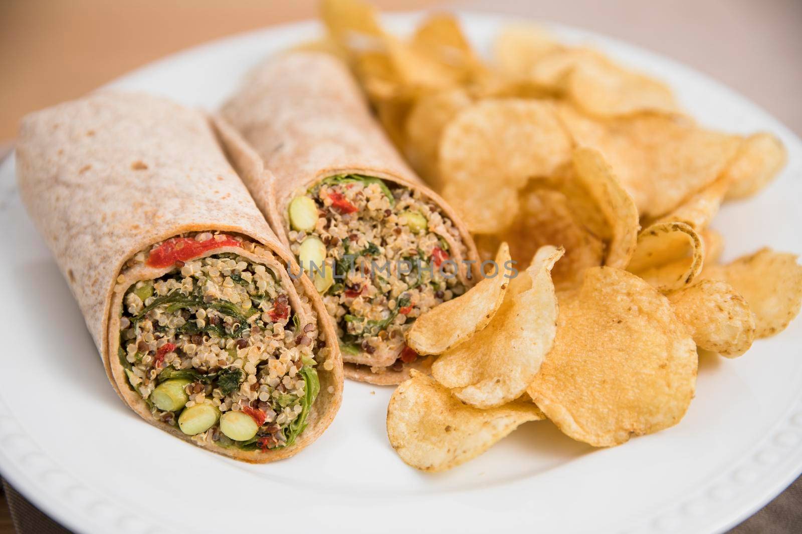 Vegan quinoa wrap served with chips.