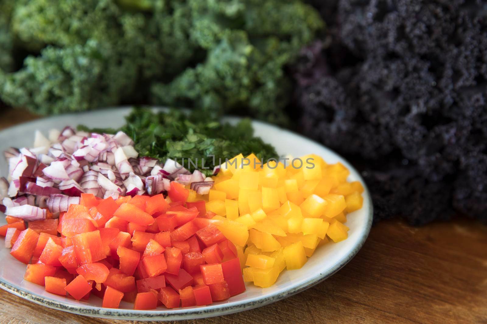 Ingredients for a healthy salad including bell peppers, onions, and kale.