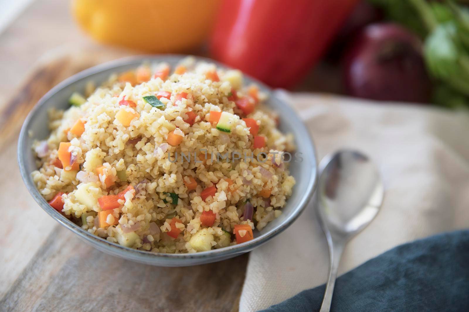 Bowl of vegan bulgur pilaf with carrots, red peppers, onions and zucchini.