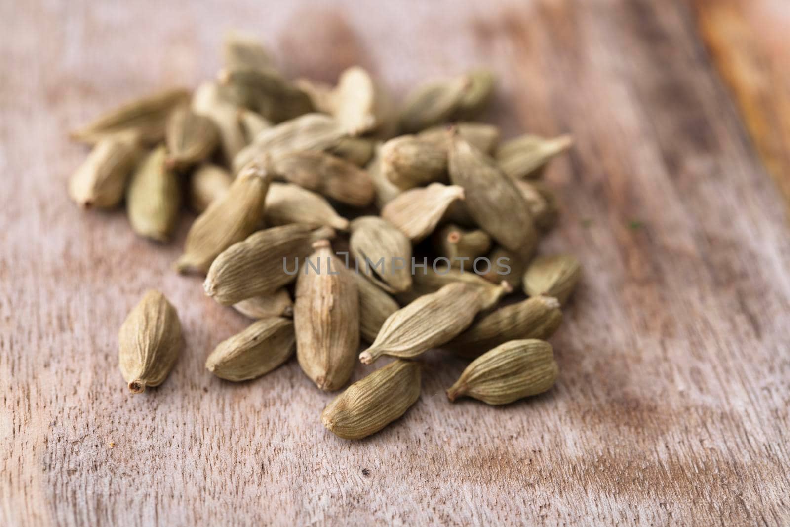 Cardamon seeds on rustic wooden surface.