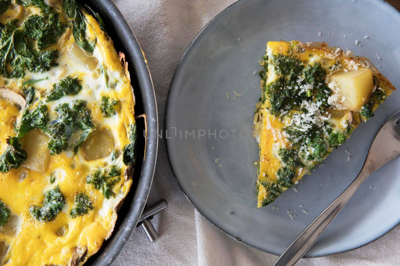 Delicious frittata with kale and potatoes in pan and slice on plate